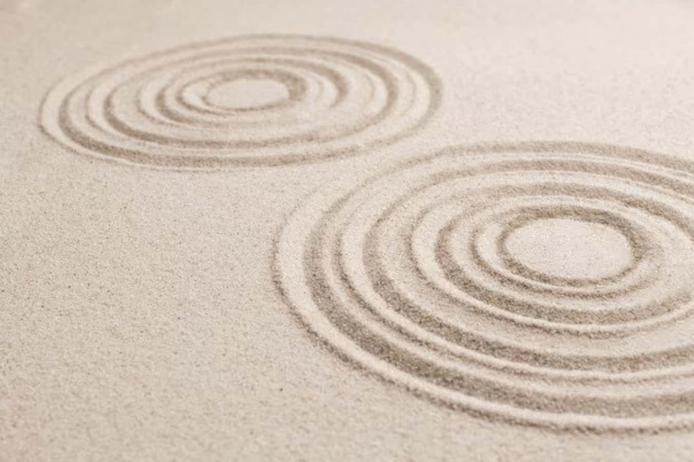 sand 桌布 壁紙 — 兩個同心圓蝕刻在細膩的米色沙子上，在極簡的禪意花園環境中喚起平靜和正念。