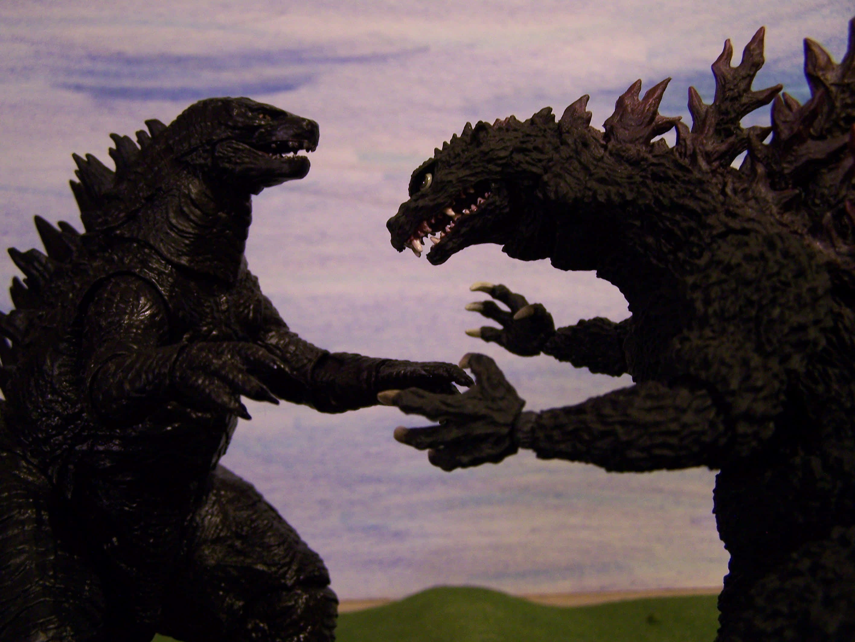 godzilla 1998 桌布 壁紙 — 兩個哥吉拉動作人偶在繪畫的天空背景下戲劇性地對峙。