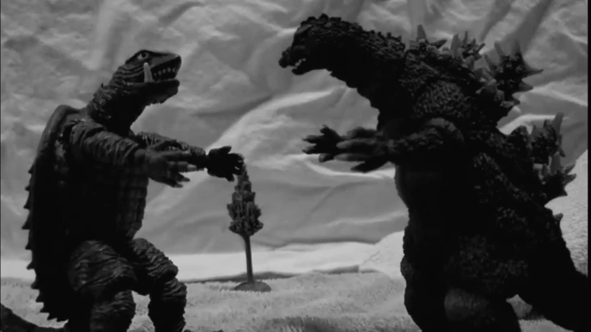 Godzilla Vs Gamera 桌布 壁紙 — 兩個哥斯拉風格的怪物公仔在一個戲劇性的黑白佈景戰鬥場景中對峙。