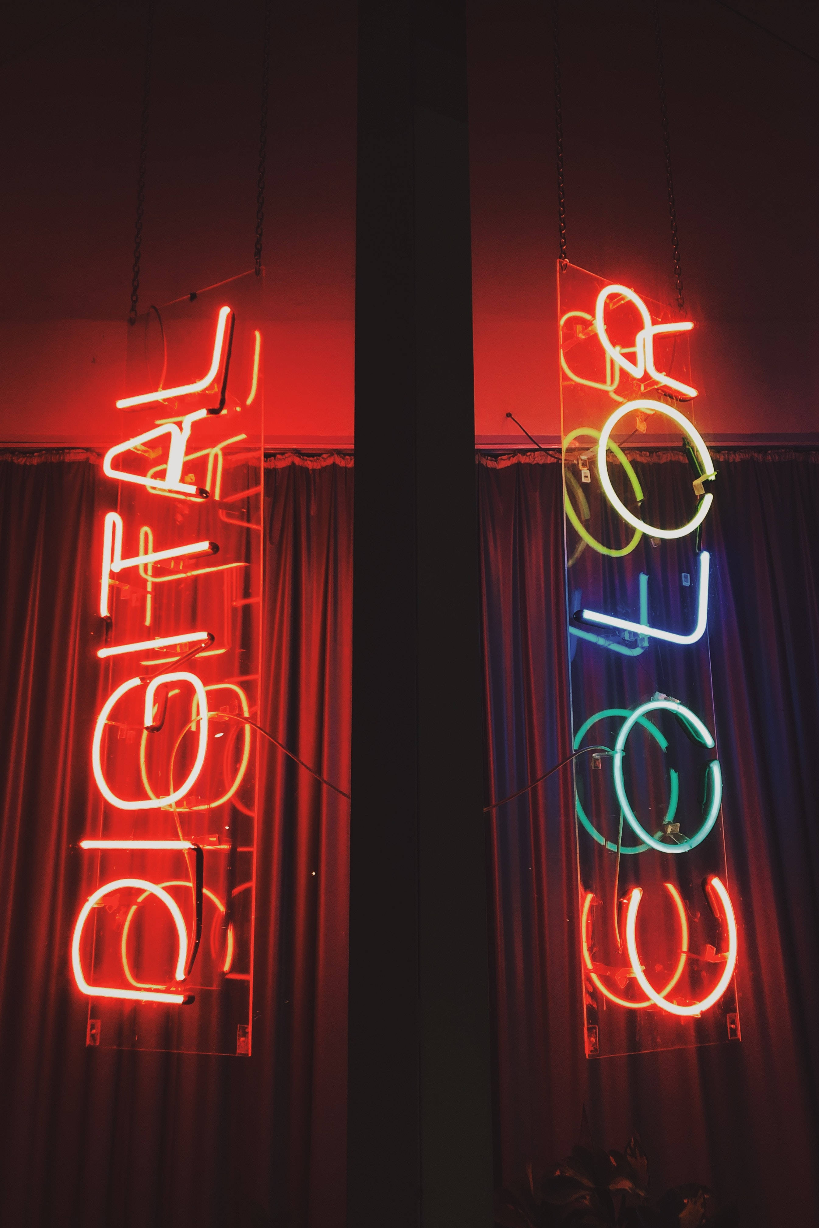 neon sign 桌布 壁紙 — 兩個垂直霓虹燈牌，以發光的紅、藍、綠色字母拼出「DIGITAL」和「COLOR」，掛在昏暗房間的深色窗簾前。