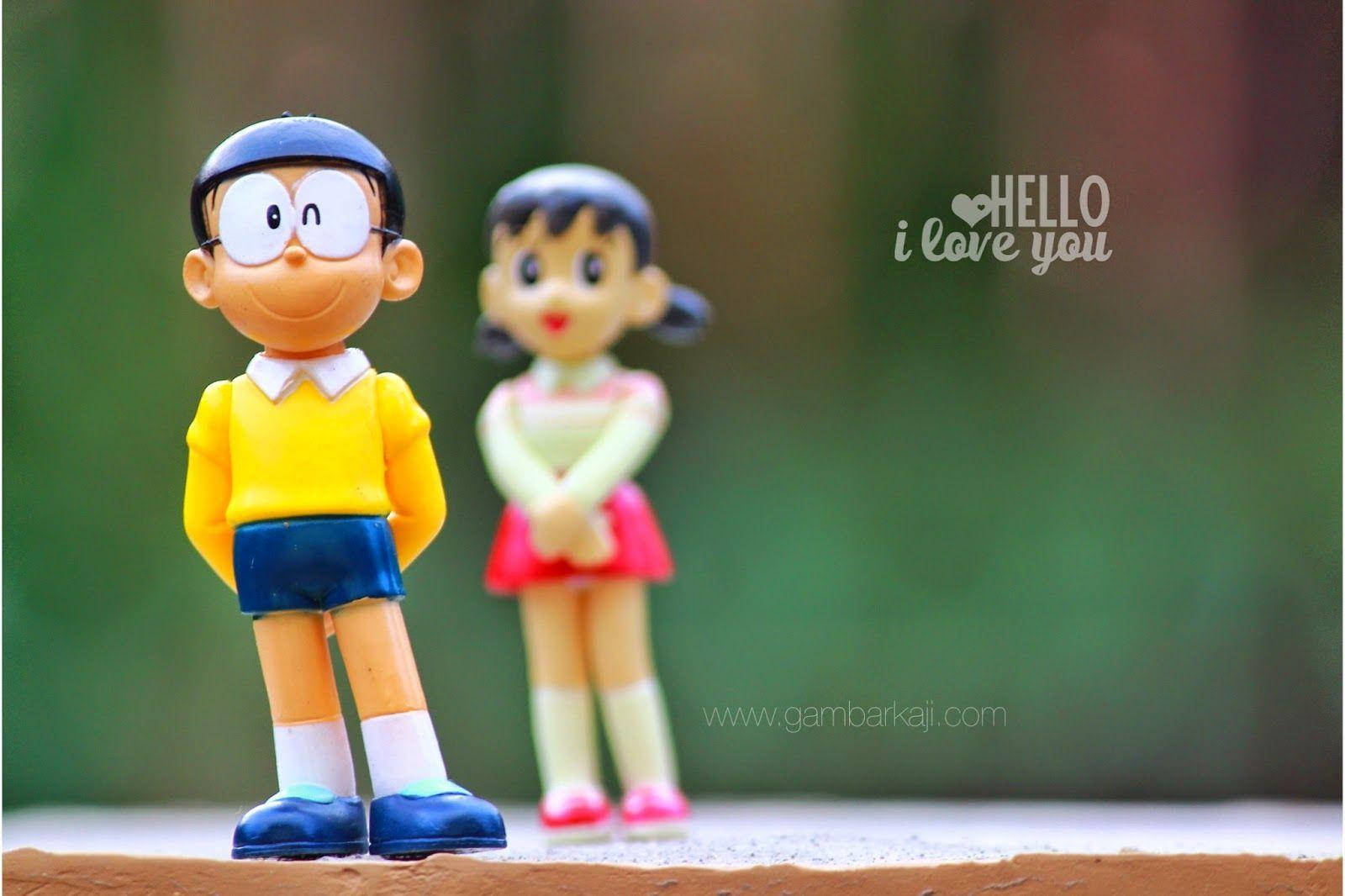 Doraemon 桌布 壁紙 — 兩個塑膠動漫公仔哆啦A夢和靜香並排站在一個模糊綠色背景的窗台上。
