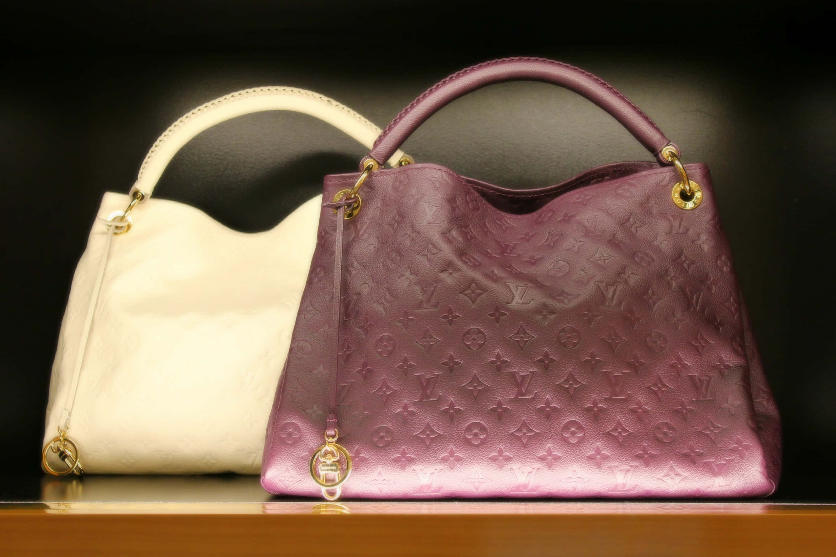 Louis Vuitton 4K 桌布 壁紙 — 兩個奢華手提包，一個奶油色一個淡紫色，搭配金色五金配件，放置在木質表面上，背景為深色。