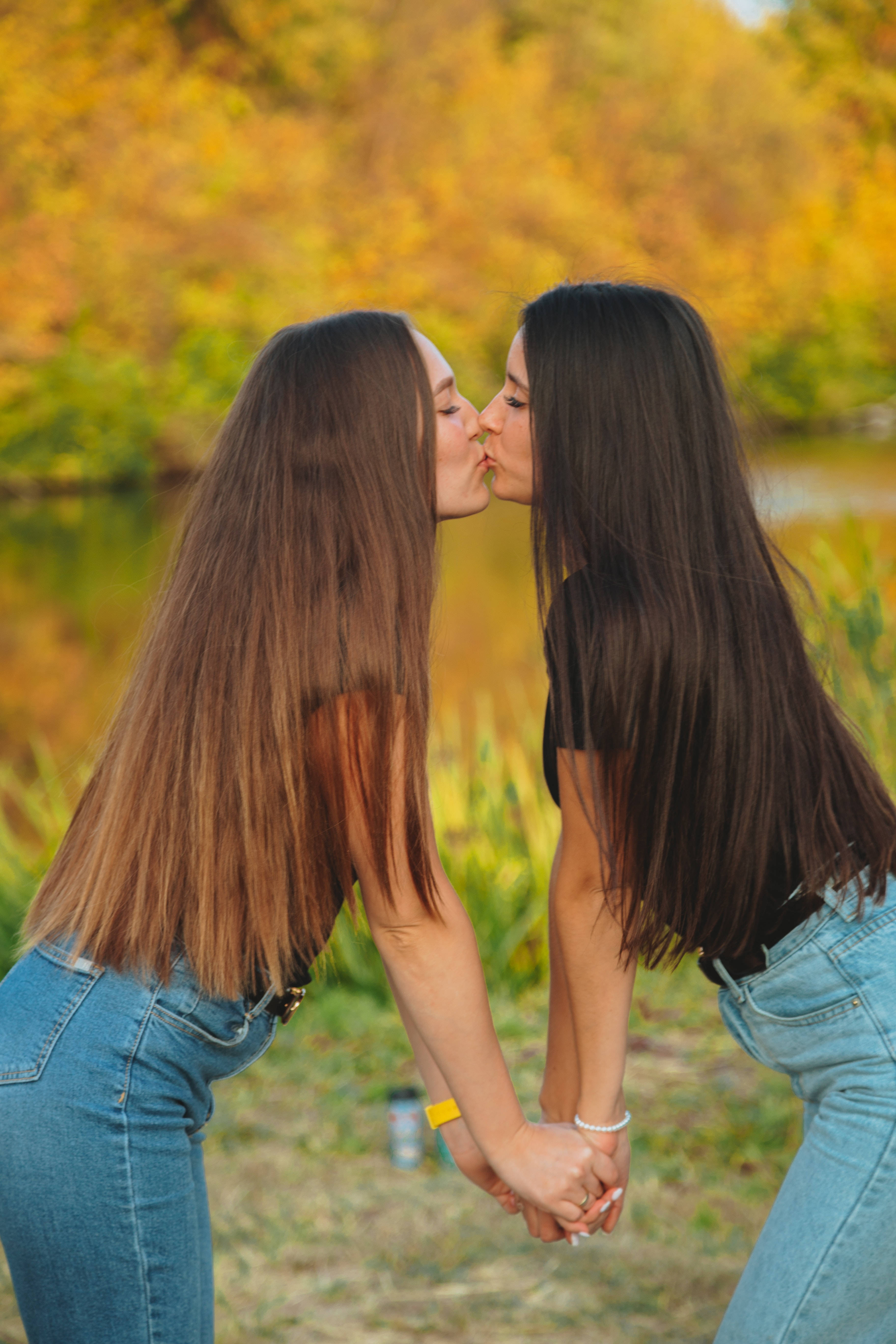 Kissing 桌布 壁紙 — 兩個女人在池塘邊溫柔地接吻，周圍是金色的秋天樹葉。