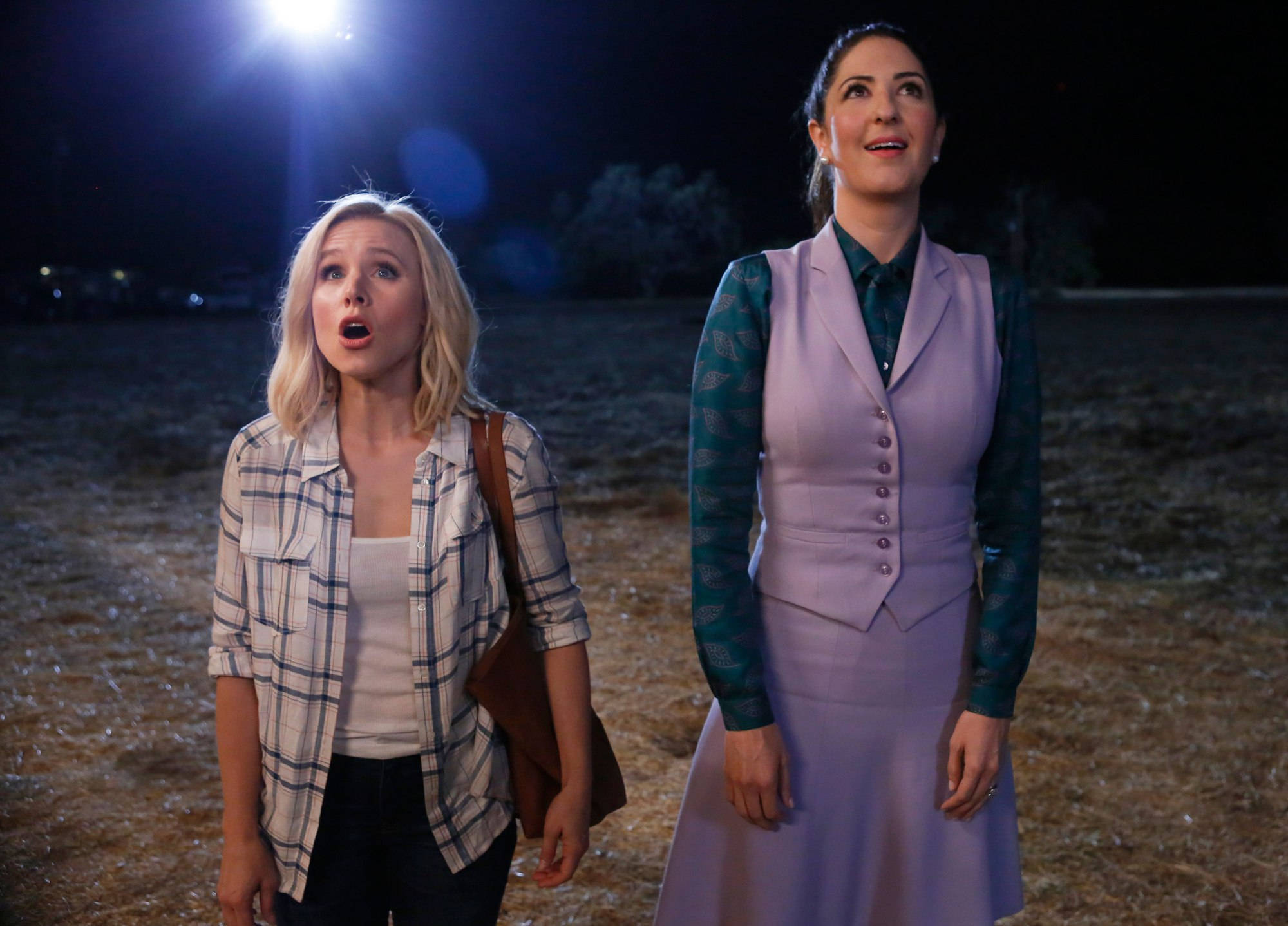 Netflix 桌布 壁紙 — 兩個女人站在黑暗的田野中，在明亮的聚光燈下，張開嘴巴敬畏地仰望看不見的東西。
