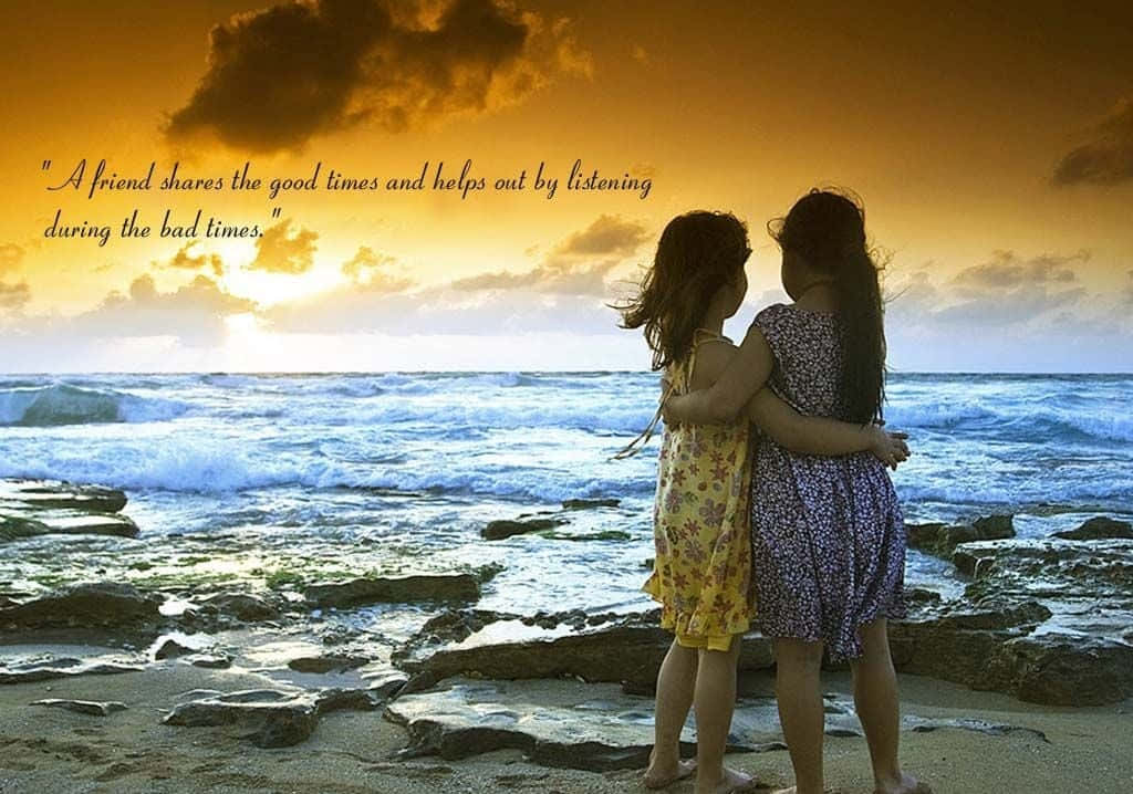 Friendship 桌布 壁紙 — 兩個女孩在岩石海灘上擁抱，金色夕陽的光芒沐浴在她們身後的海洋波浪上。