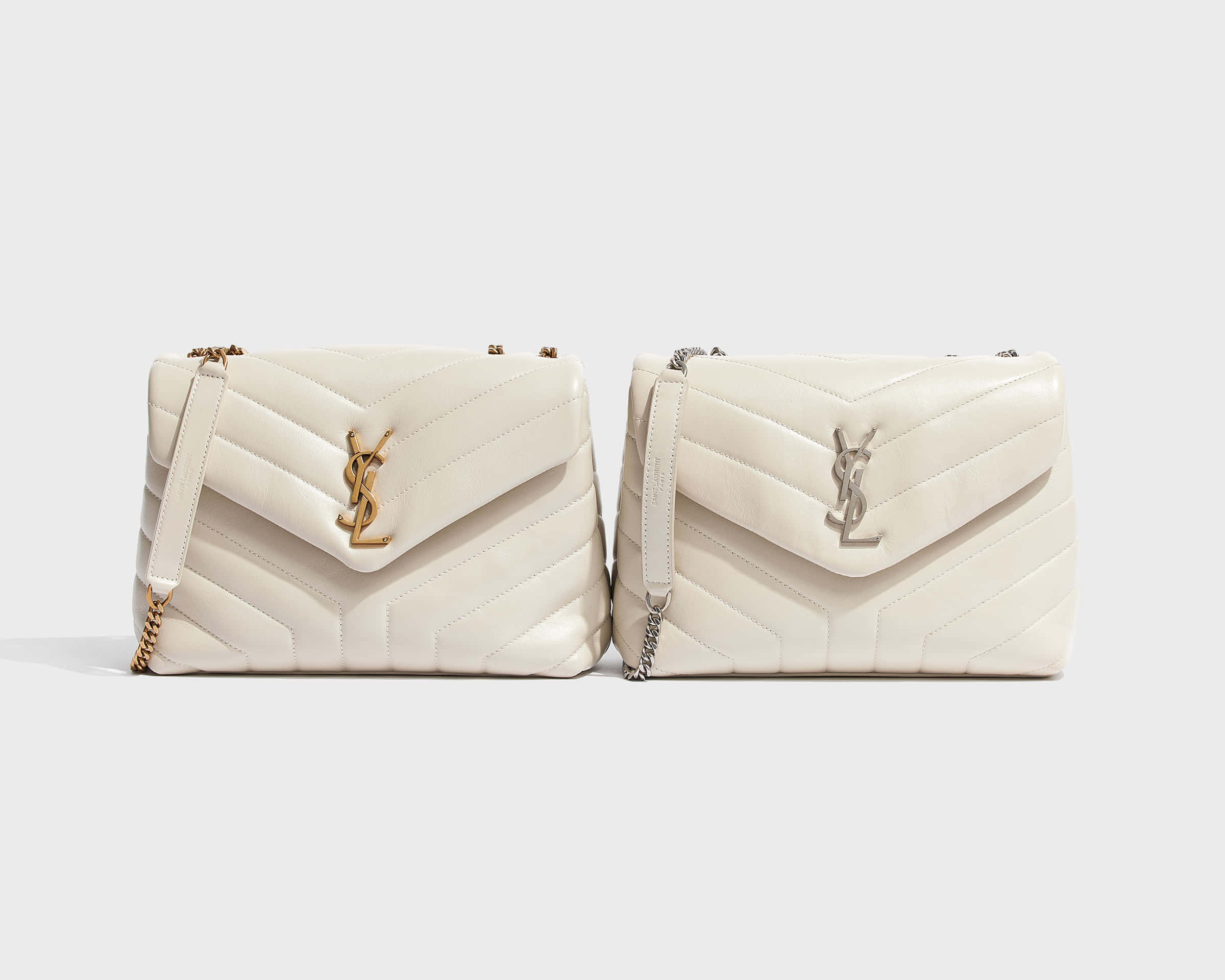 YSL 桌布 壁紙 — 兩個奶油色絎縫YSL手袋，配有金色和銀色五金件，並排放在純白色背景上。
