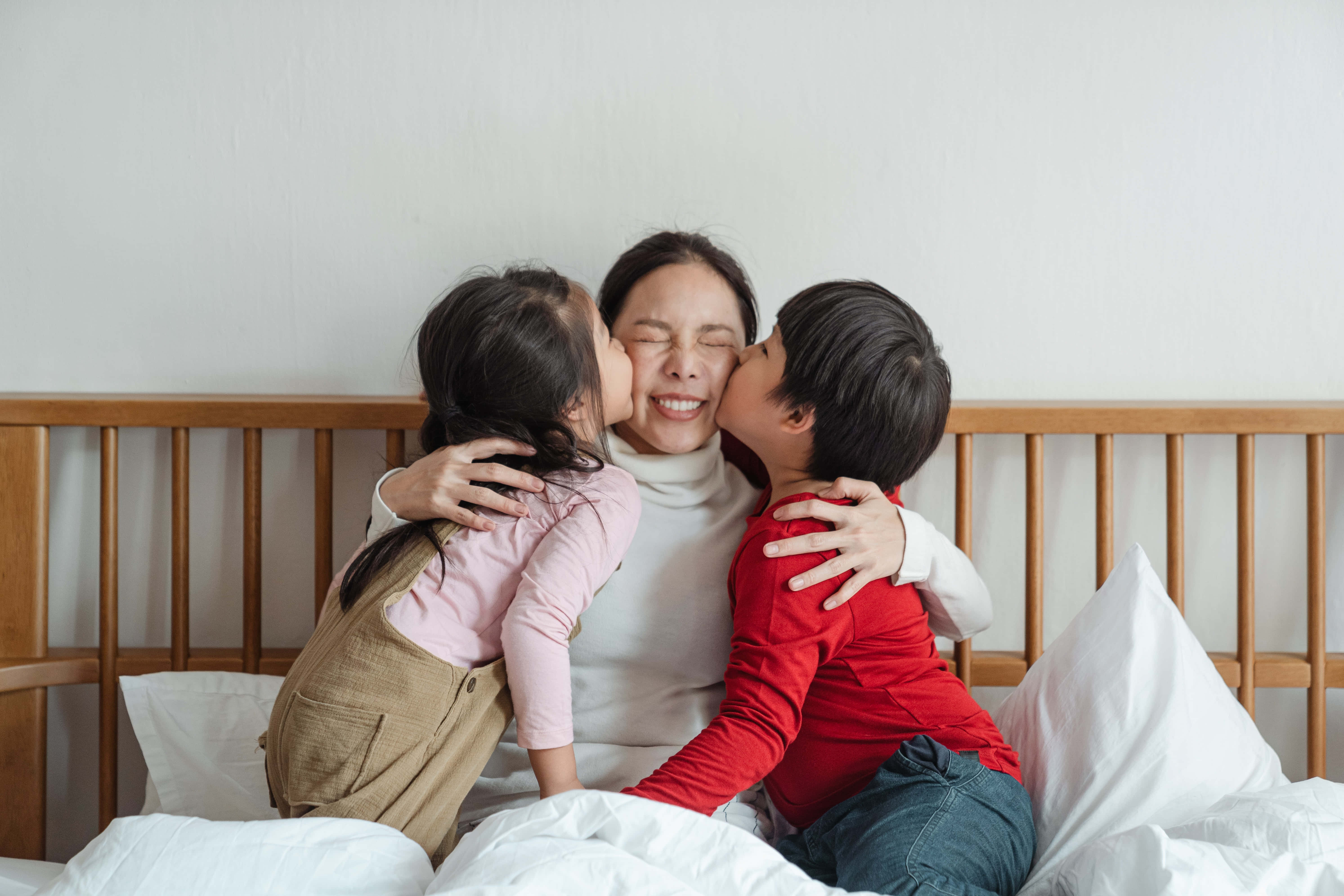 Kiss 桌布 壁紙 — 兩個孩子依偎在木床上，深情地親吻微笑的母親的臉頰。