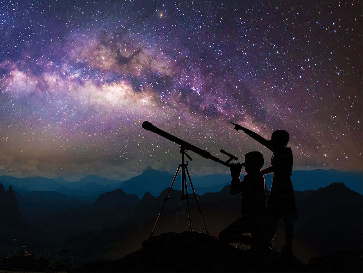夜空 桌布 壁紙 — 兩個孩子剪影在充滿活力的紫色和粉紅色銀河系前，下方有山脈。