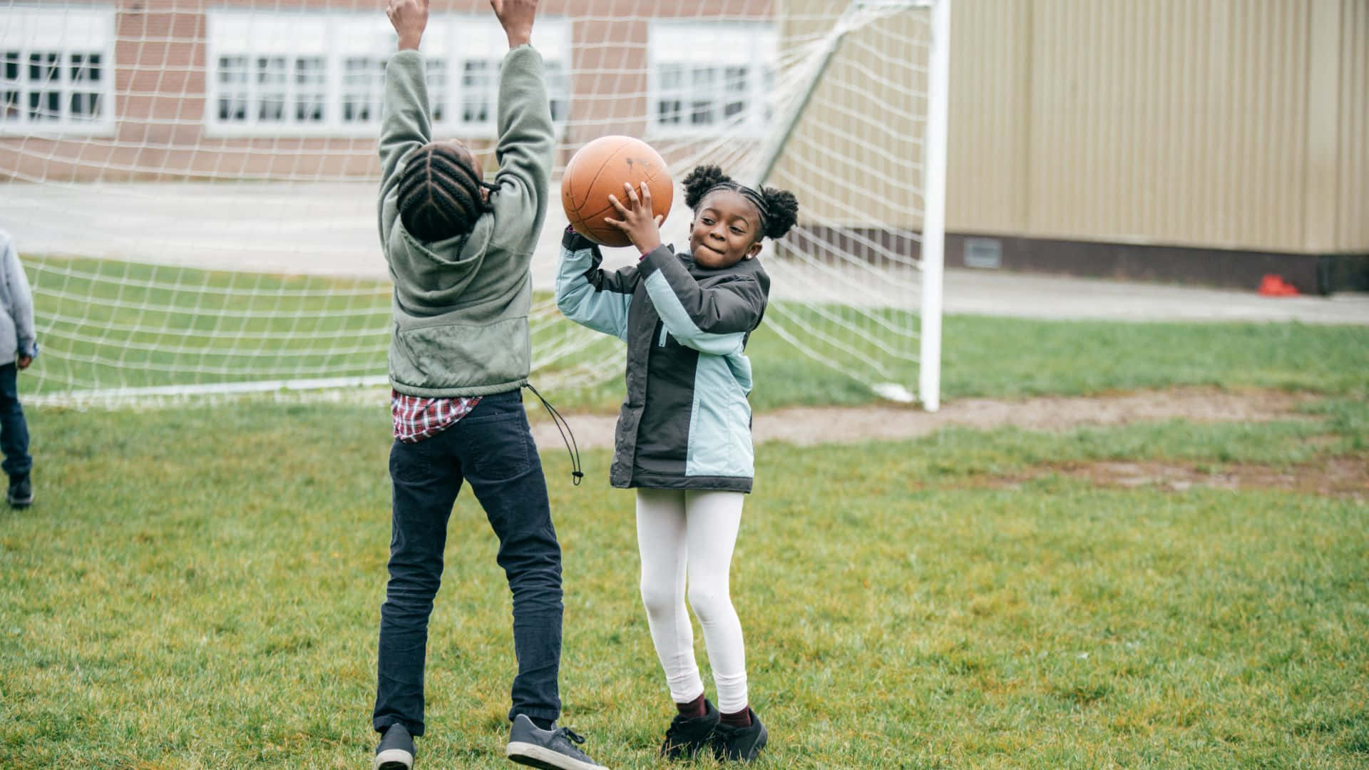 Best Sports 桌布 壁紙 — 兩個孩子在草地上打籃球，身後有一個足球球門。