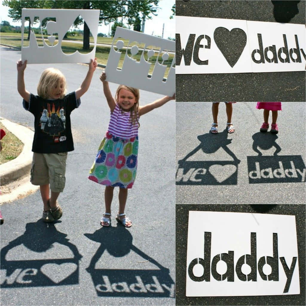 Fathers Day 桌布 壁紙 — 兩個孩子高興地舉起模板，在陽光明媚的瀝青路上投射出「我們愛爸爸」的影子。