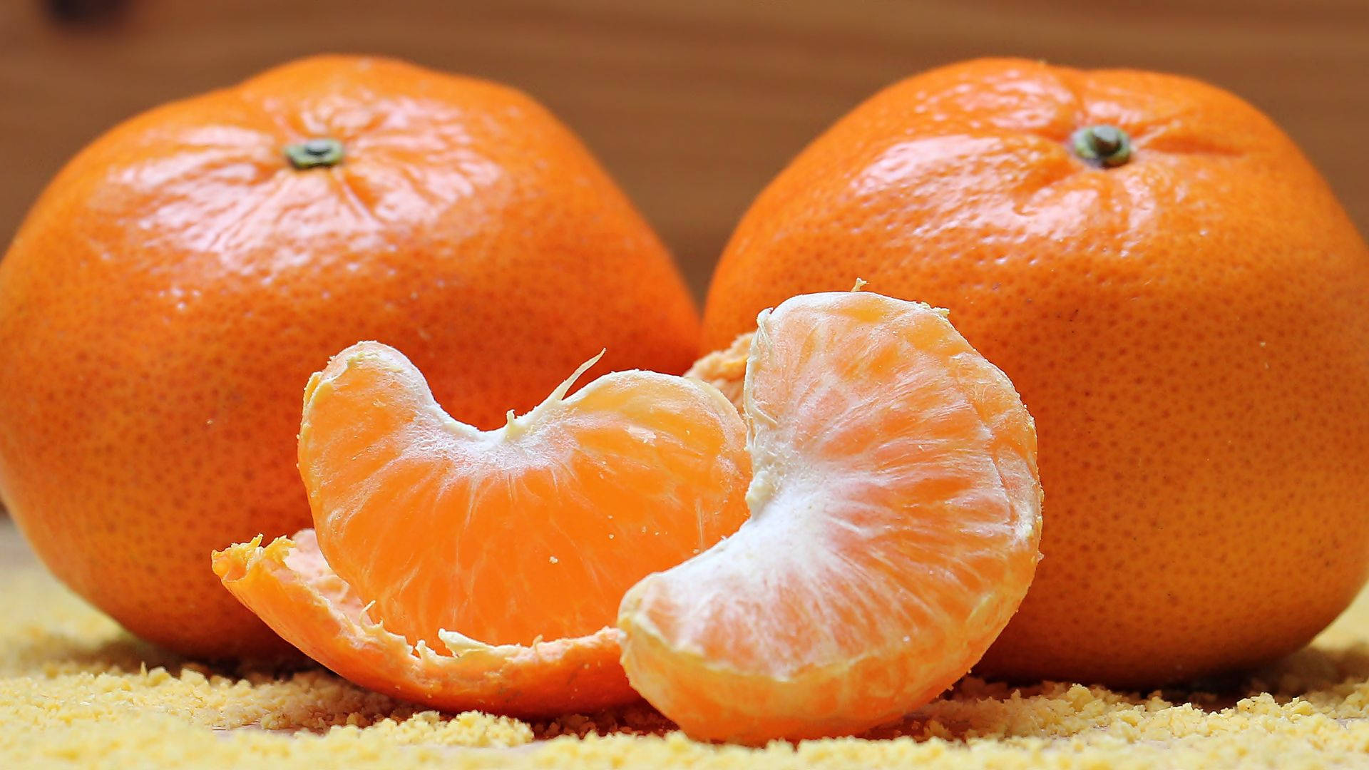 Orange Fruit 桌布 壁紙 — 兩個完整的柑橘和剝好的瓣片放在橙皮床上，背景是溫暖的木質。