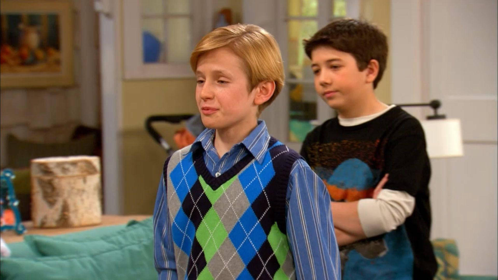 Good Luck Charlie 桌布 壁紙 — 兩個小男孩站在舒適的客廳裡，一個穿著彩色菱形圖案毛衣，另一個交叉雙臂，看起來很不耐煩。