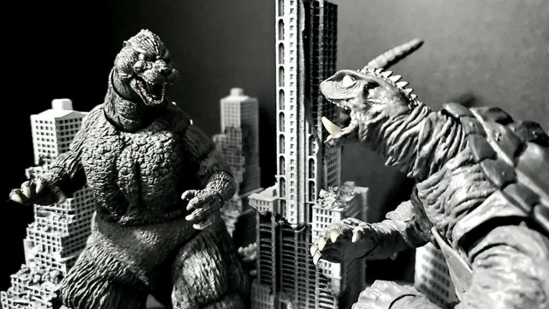 Godzilla Vs Gamera 桌布 壁紙 — 兩個巨型怪獸公仔在微型摩天大樓之間激烈碰撞，形成一個戲劇性的黑白立體模型場景。