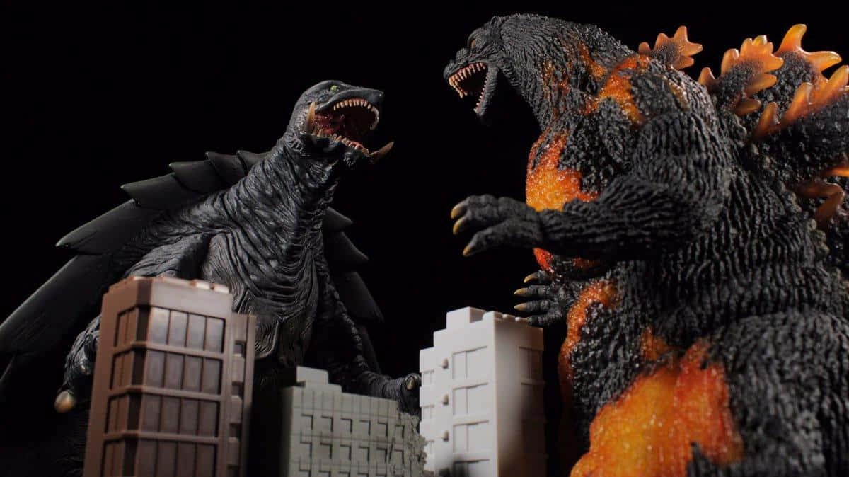 Burning Godzilla 桌布 壁紙 — 兩個巨型怪獸模型哥吉拉和王者基多拉在黑色背景下的微型城市建築中互相咆哮。