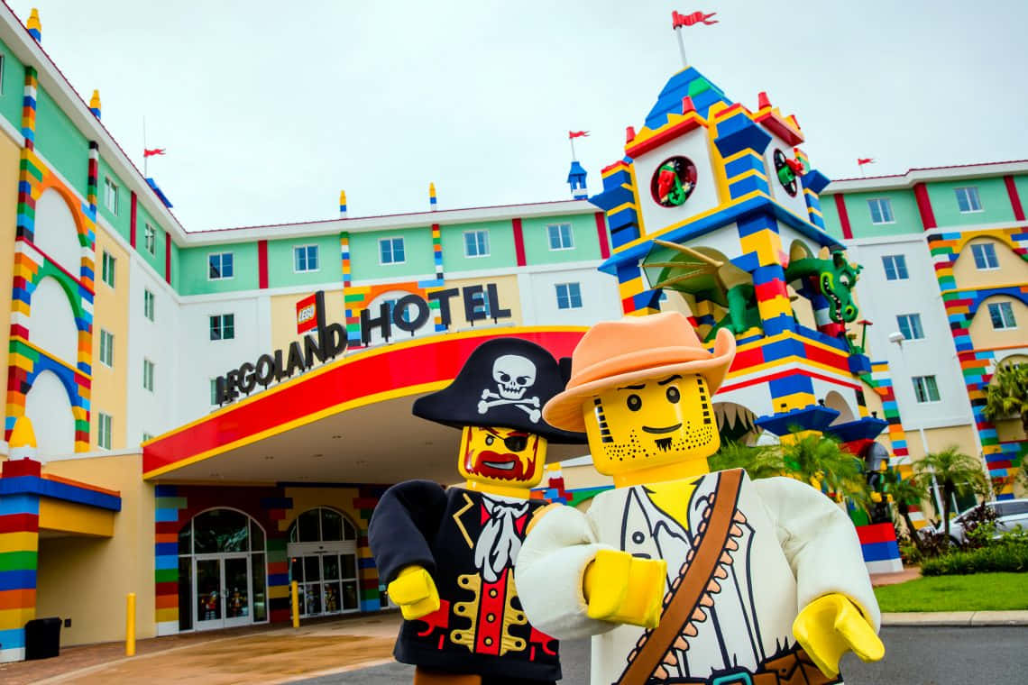 Legoland 桌布 壁紙 — 兩個巨大的 LEGO 海盜迷你人偶自豪地站在色彩繽紛的 LEGO 飯店前，飯店擁有塊狀建築風格和有趣的旗幟。