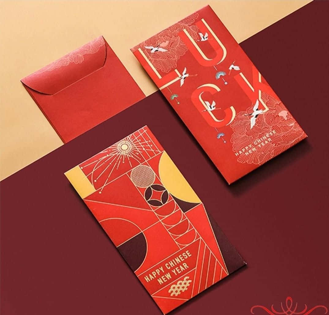 Red Envelope 桌布 壁紙 — 兩個帶有幾何和鳥類圖案的紅色中國新年紅包，放在栗色和米色的表面上。
