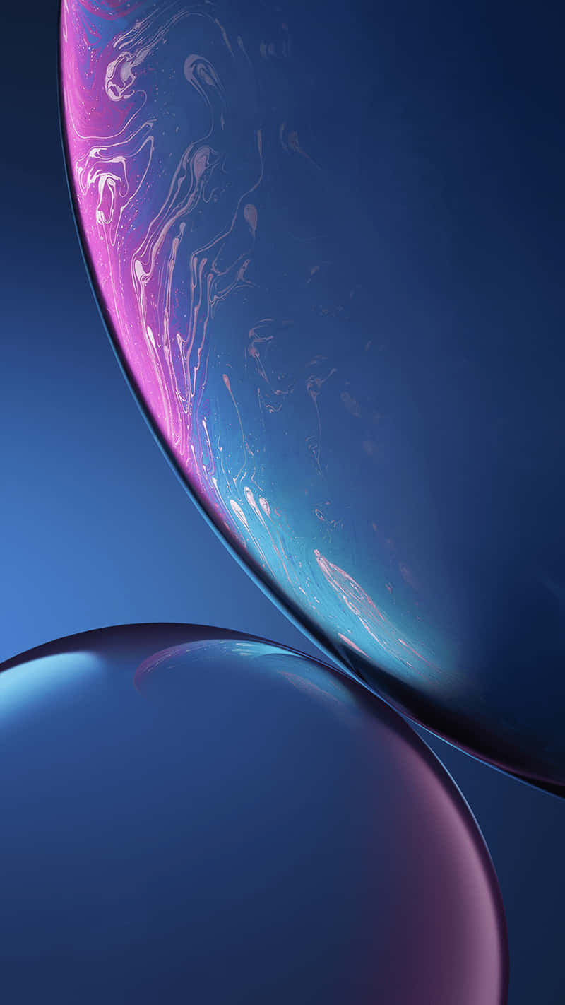 Apple iPhone Xs 桌布 壁紙 — 兩個帶有旋轉粉紅色和藍色液體圖案的光澤球體漂浮在深藍色漸變背景上。