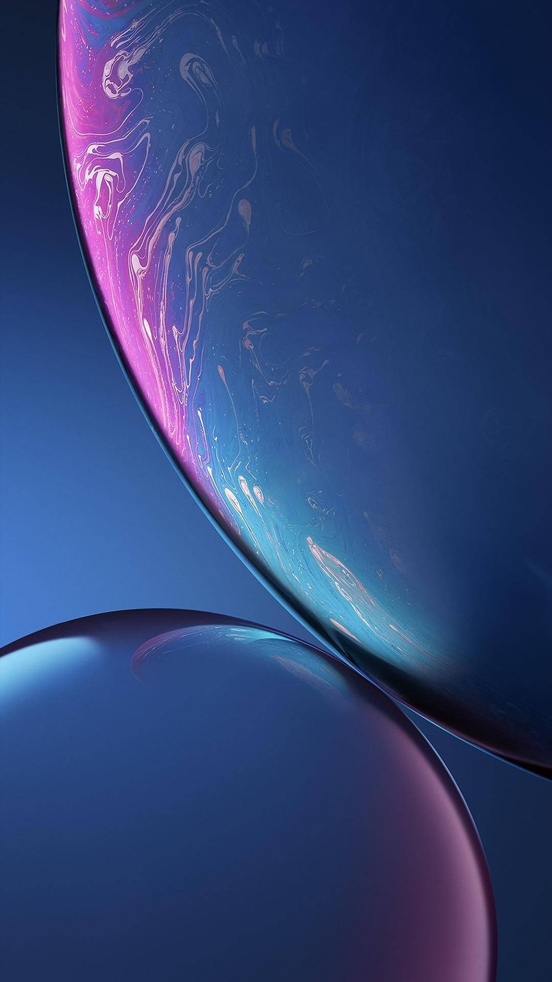 iPhone XR 桌布 壁紙 — 兩個帶有旋轉粉紅色和藍色虹彩圖案的光滑球體，漂浮在深藍色漸變背景上。