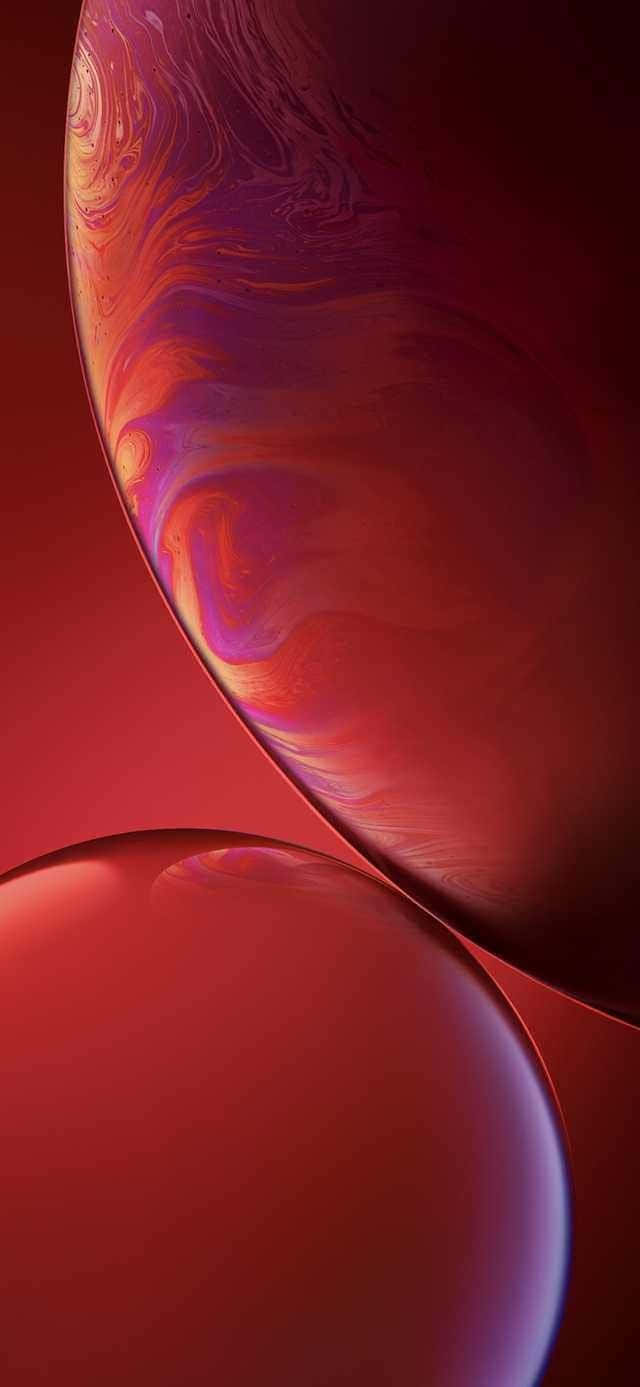 紅色 iPhone 桌布 壁紙 — 兩個帶有旋轉紅色、紫色和橙色液體圖案的光澤球體漂浮在深紅色背景上。