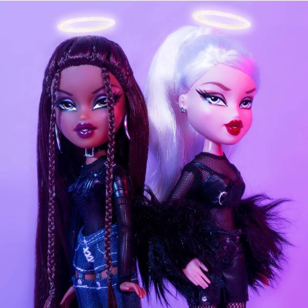 Bratz 桌布 壁紙 — 兩個帶有發光光環的 Bratz 公仔，在紫色背景前穿著前衛的黑色服裝。