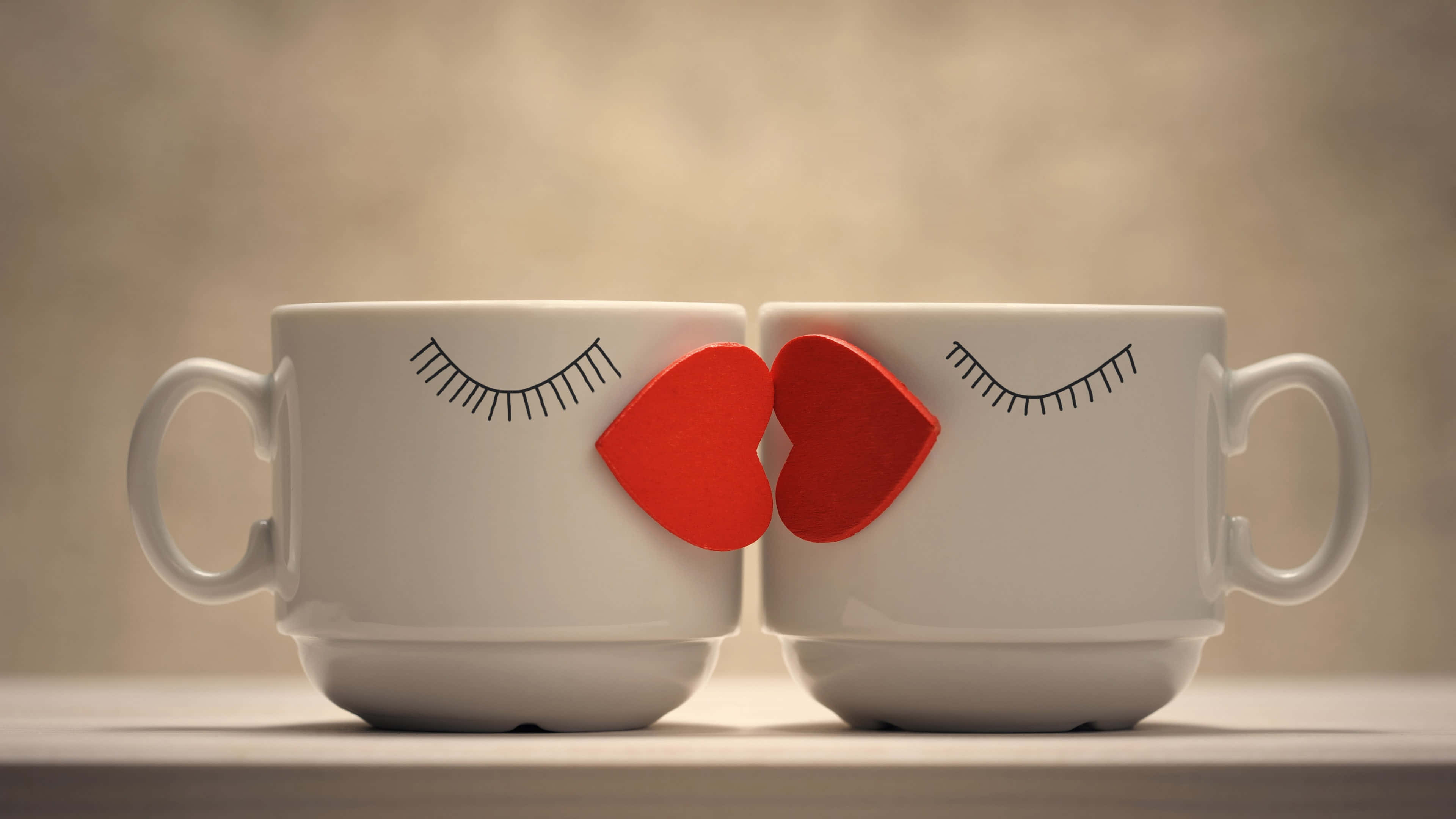 4K Love 桌布 壁紙 — 兩個帶有睫毛和紅色心形的白色馬克杯在柔和的米色背景上互相親吻。