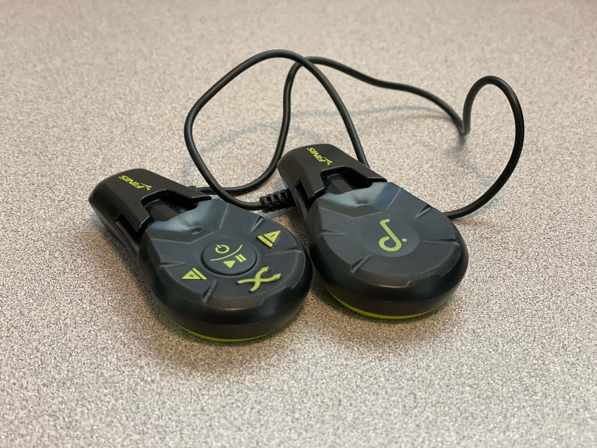 Music Player 桌布 壁紙 — 兩個帶有萊姆綠色符號的黑色 Zync 遙控器，通過螺旋電線連接，放在有斑點的灰色表面上。