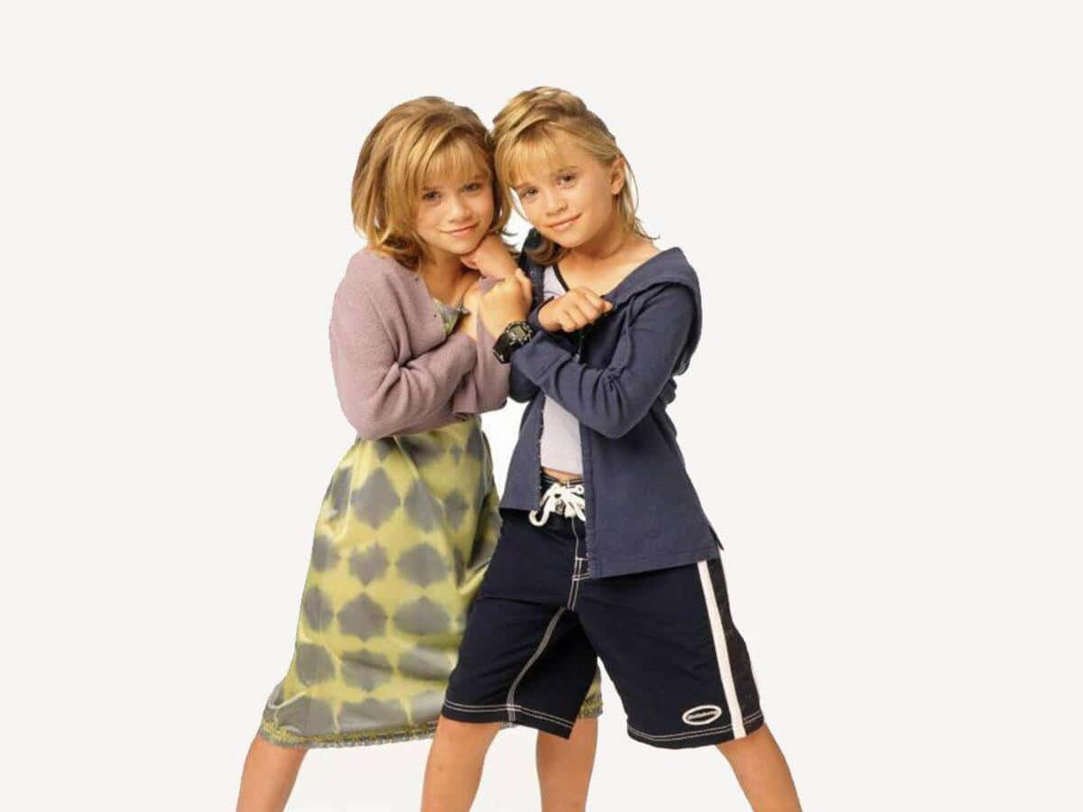 Mary Kate Olsen 桌布 壁紙 — 兩個年幼的孩子在純白色背景前擺出俏皮的姿勢，露出燦爛的笑容，穿著休閒服裝。