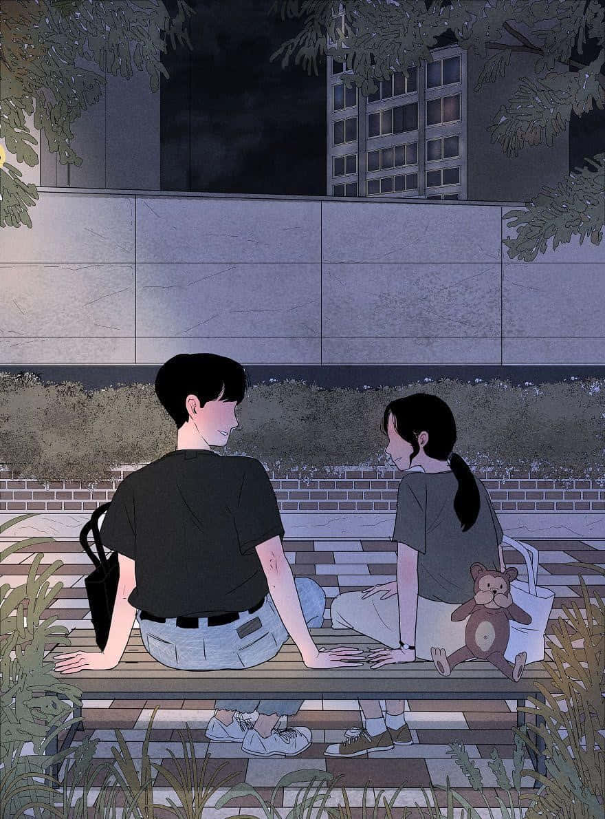 可愛動漫情侶 桌布 壁紙 — 兩個年輕人夜晚並排坐在長椅上，周圍是樹葉和城市建築，在昏暗燈光下分享寧靜的親密時光。