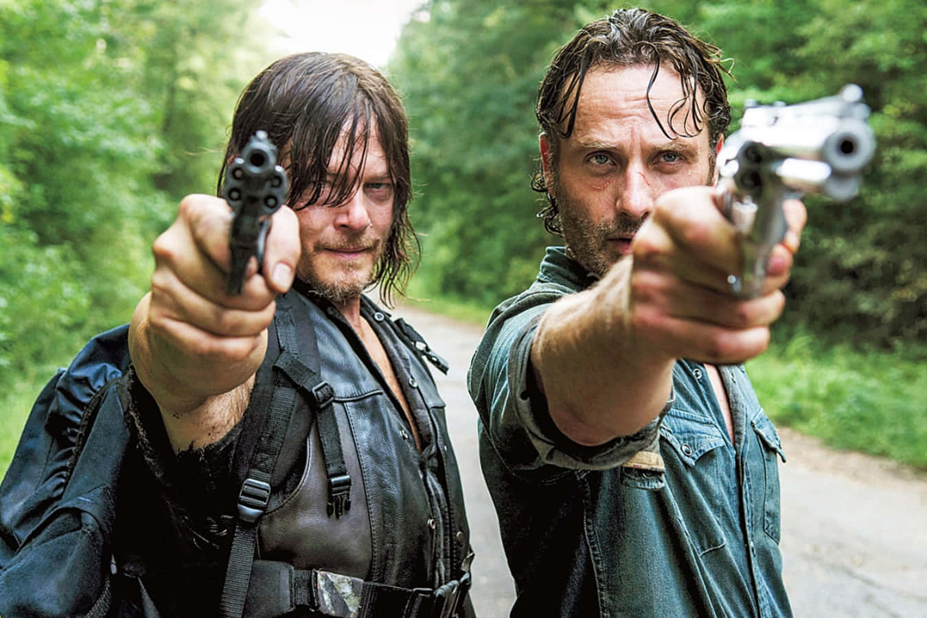 walking dead 桌布 壁紙 — 兩個強壯的男人濕著頭髮，在森林路上直接用手槍瞄準觀眾。