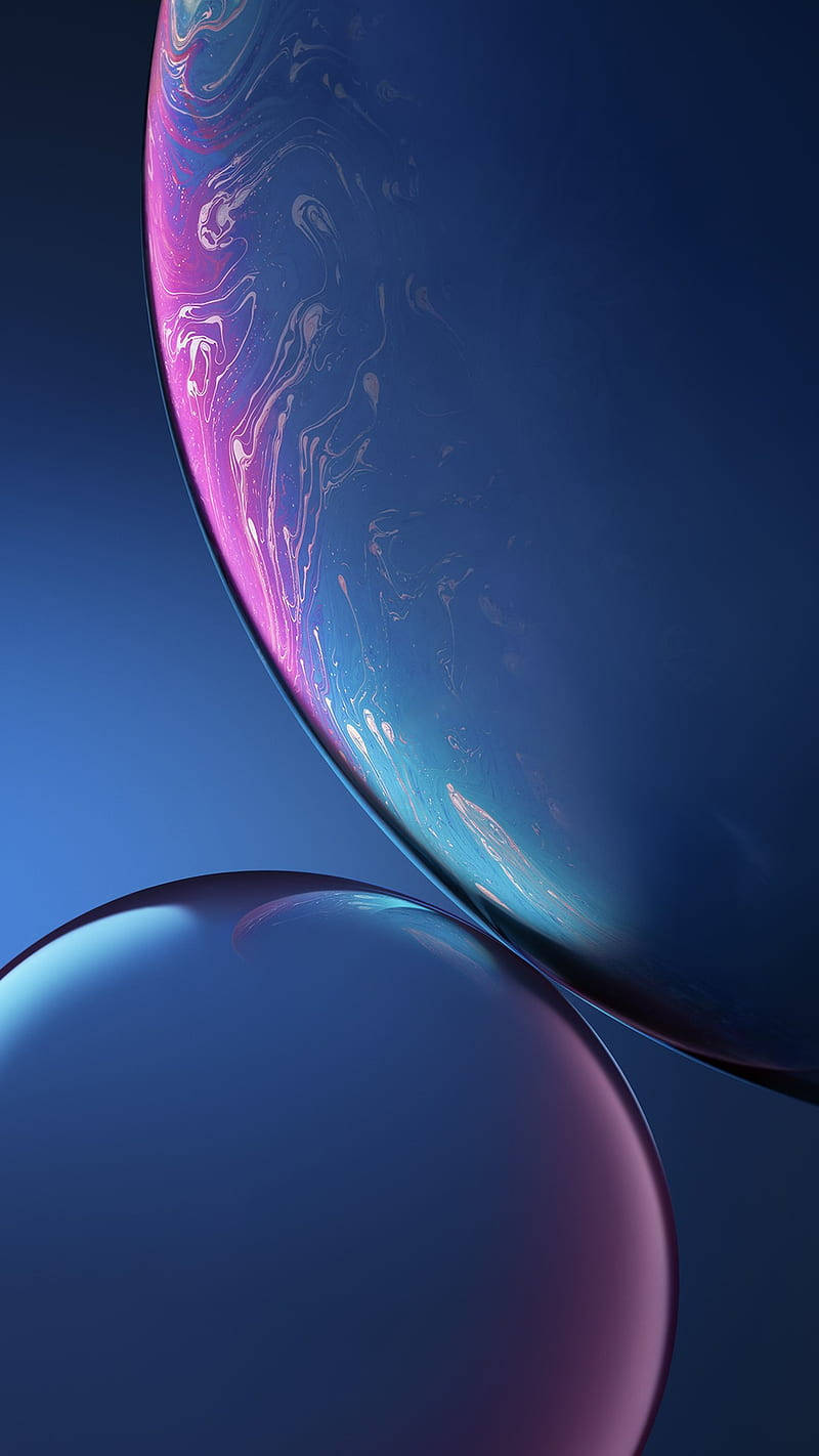 Apple iPhone 預設 桌布 壁紙 — 兩個彩虹色的肥皂泡漂浮在深藍色漸變背景上，帶有旋轉的粉紅色和青色色調。