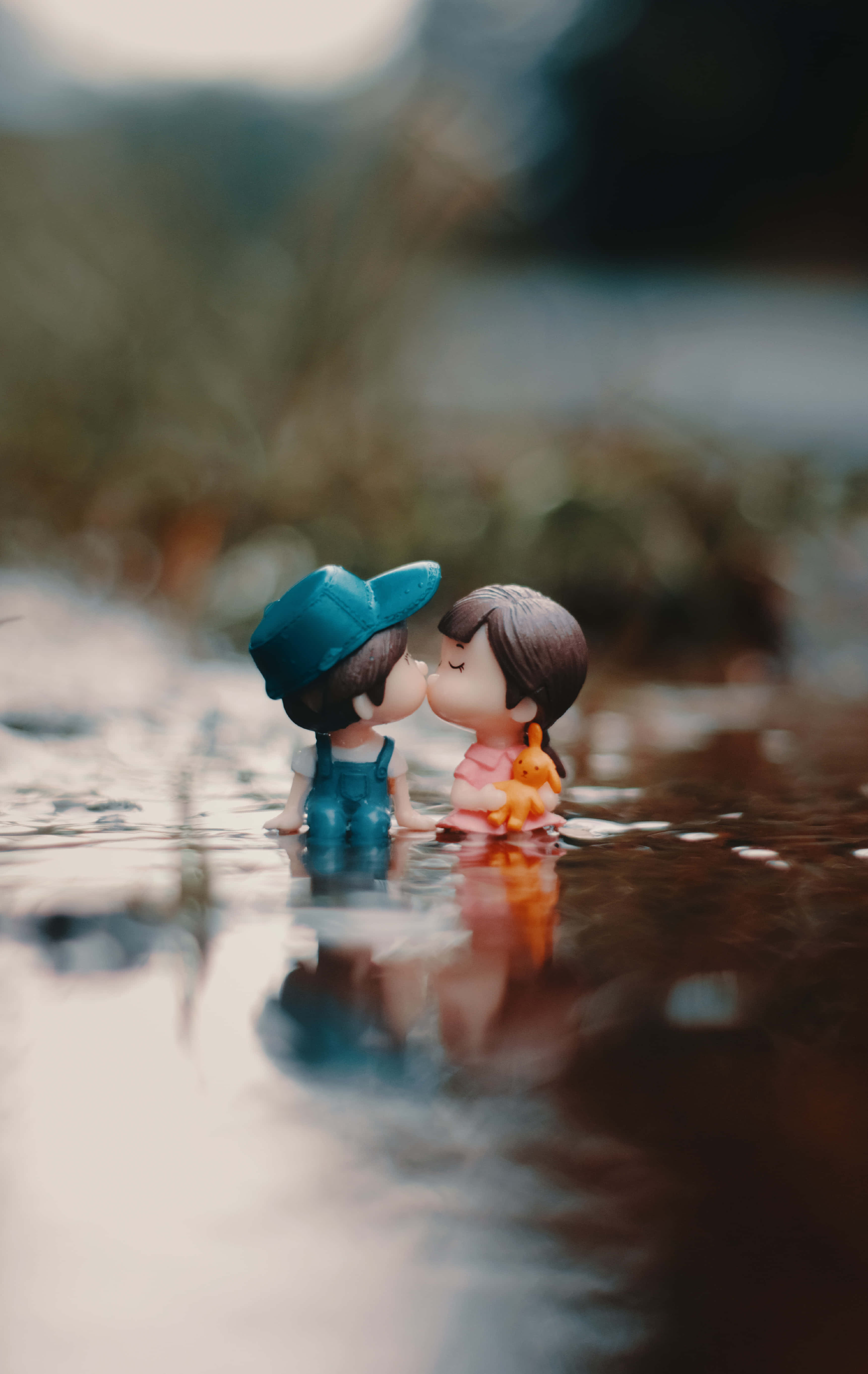 Cute Love 桌布 壁紙 — 兩個微型公仔在淺水中接吻，背景柔和模糊，倒影輕柔。