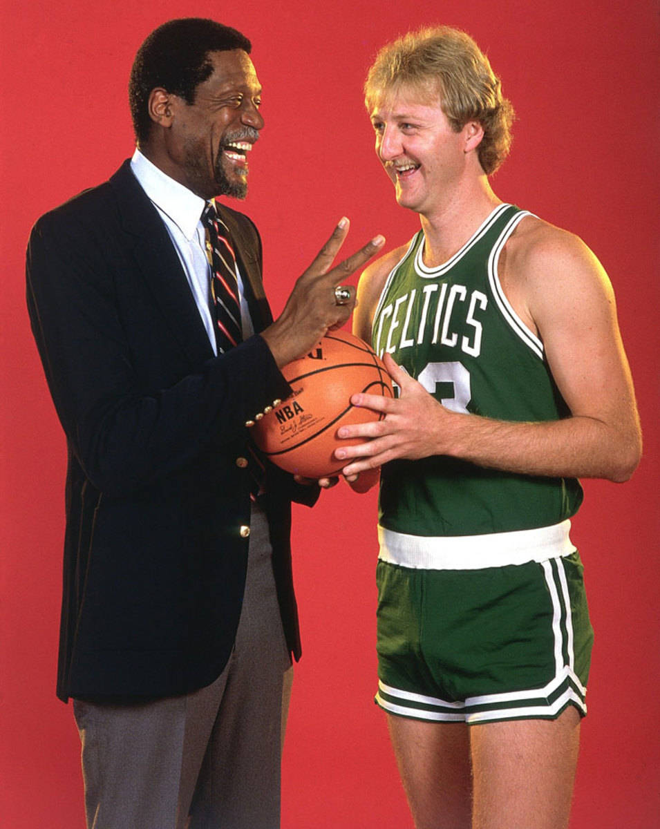 Boston Celtics 桌布 壁紙 — 兩個微笑的男人，一個西裝筆挺拿著籃球，另一個穿著綠色塞爾提克球衣，兩人在純紅色背景前擺姿勢。