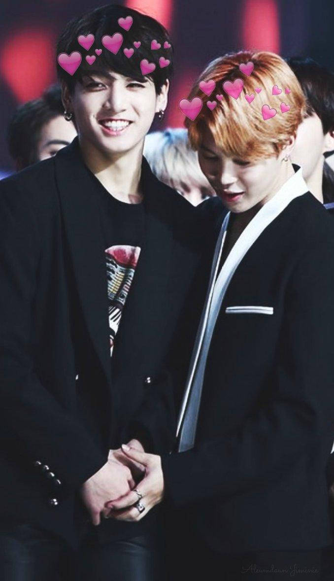 Jikook 桌布 壁紙 — 兩個微笑的黑西裝男人牽手，粉紅色心形圖案漂浮在他們頭頂，背景是模糊的紅色。