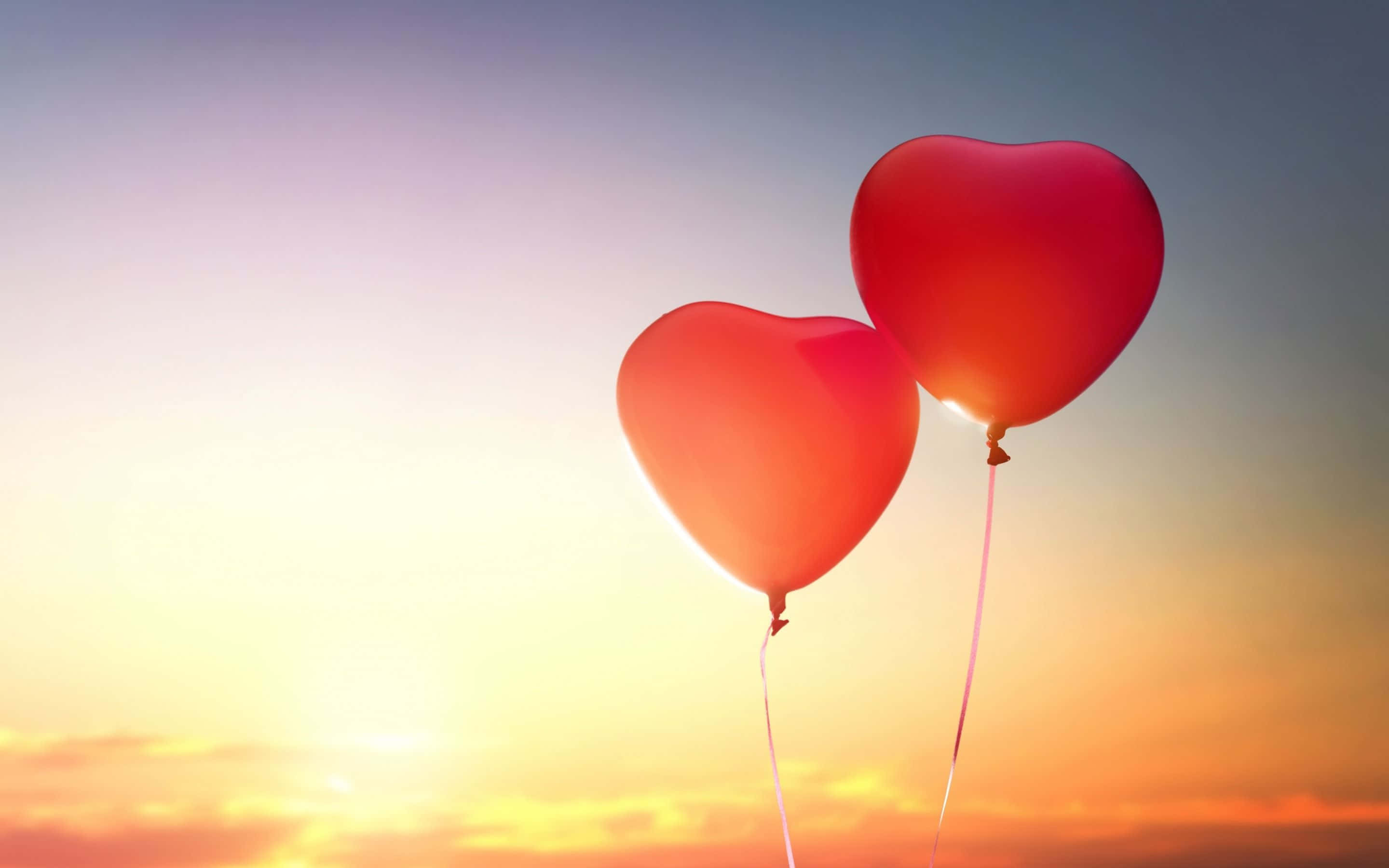 Balloon 桌布 壁紙 — 兩個心形紅色氣球在溫暖的日落天空下飄浮，帶有柔和的金色和紫色色調。