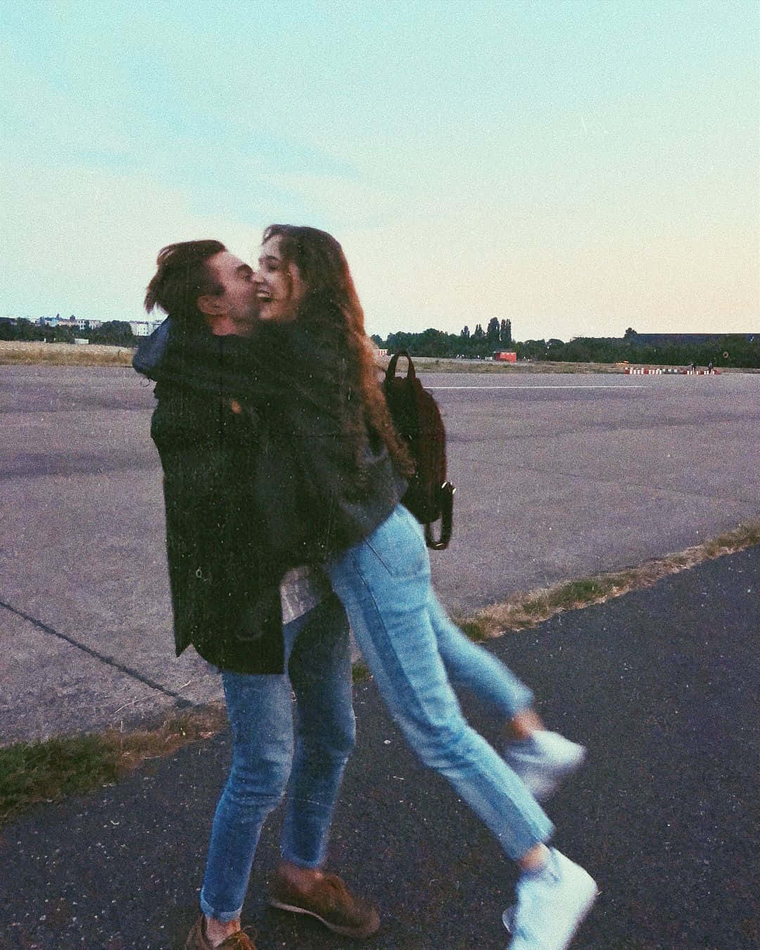 Relationship 桌布 壁紙 — 兩個快樂的人在柔和的暮色天空下，在瀝青跑道上擁抱旋轉。