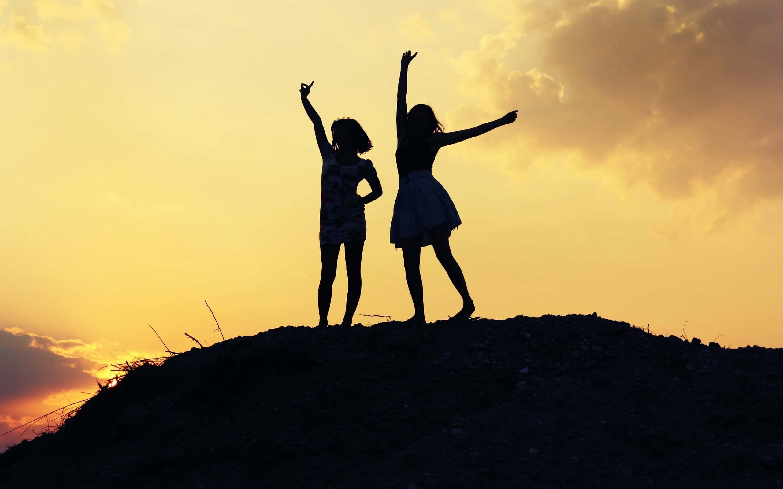 Friends 桌布 壁紙 — 兩個快樂的女孩剪影在山丘頂上舉起雙臂擁抱金色的日落天空。