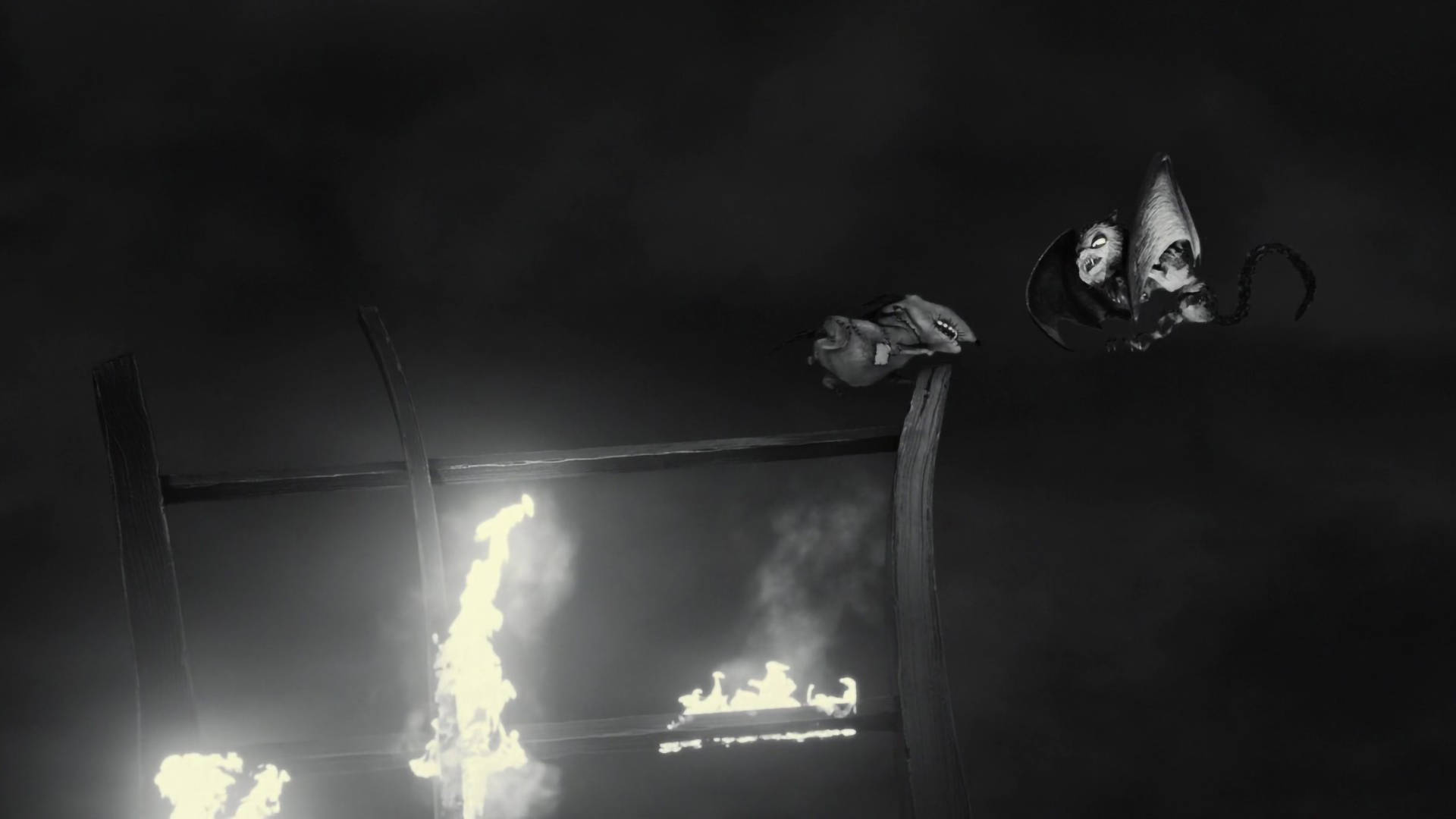 Frankenweenie 桌布 壁紙 — 兩個怪誕的生物棲息在一個燃燒的木結構頂部，背景是黑暗煙霧瀰漫的夜空。