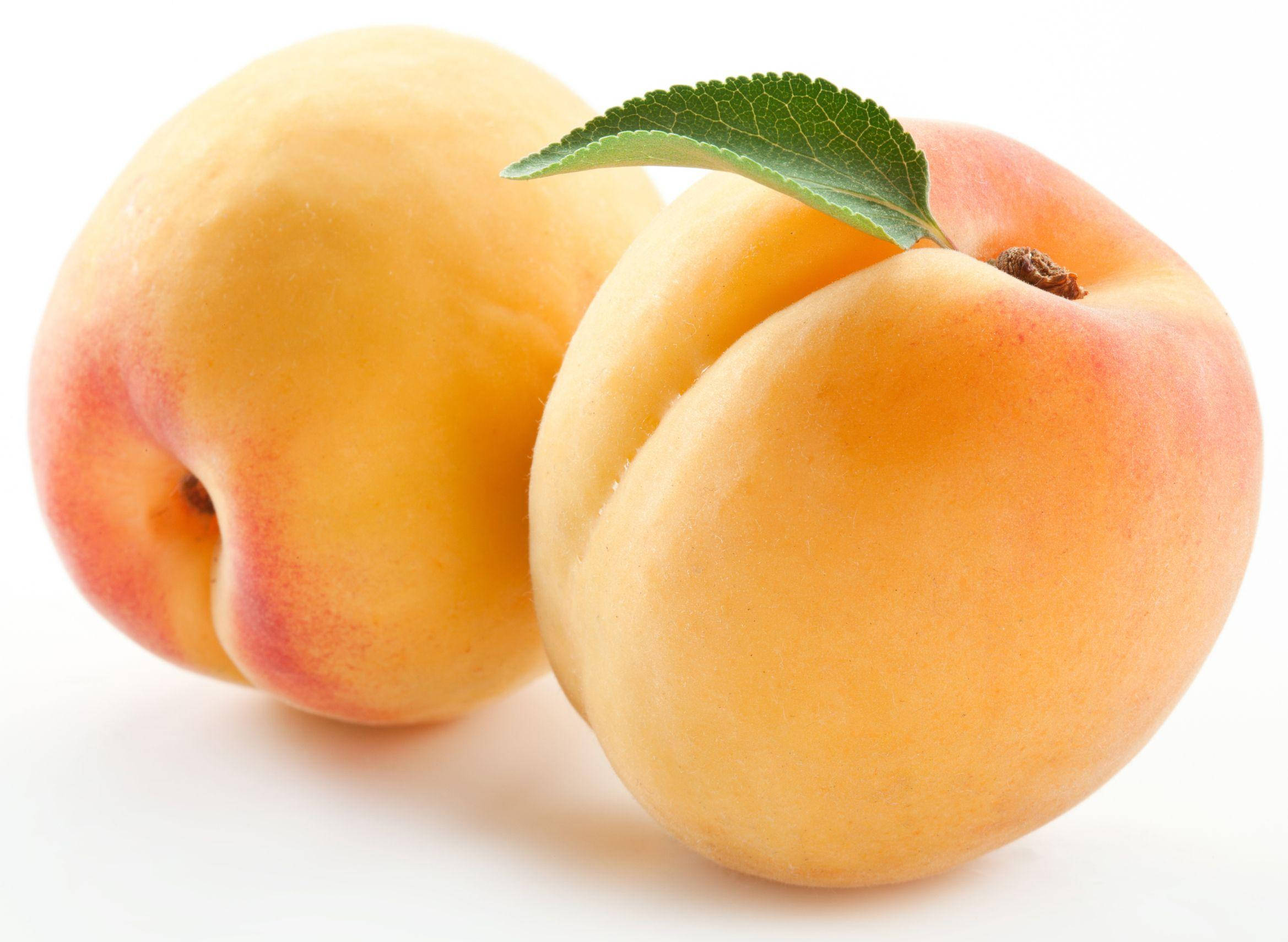 Fruit 桌布 壁紙 — 兩個成熟的桃子，帶有柔軟的桃皮和一片綠色的葉子，放在乾淨的白色背景上。