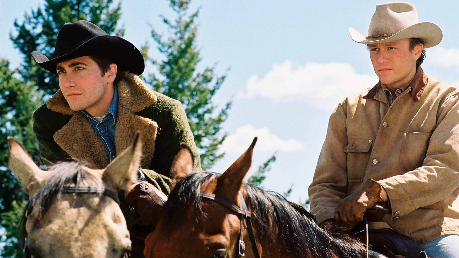 brokeback mountain 桌布 壁紙 — 兩個戴牛仔帽的男人騎著馬，在明亮的藍天下，身後有蓬鬆的白雲和綠色的松樹。