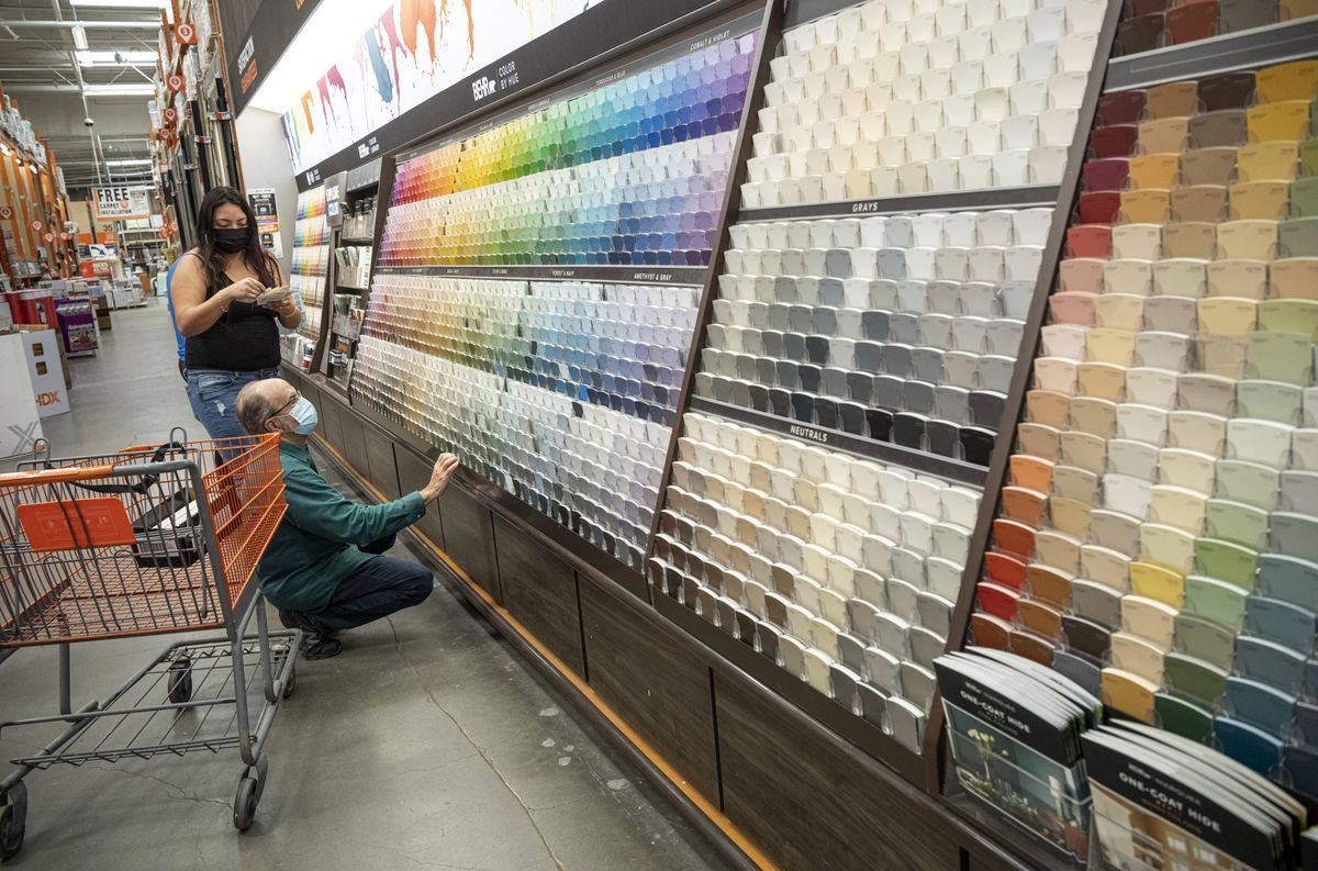 Home Depot 桌布 壁紙 — 兩個戴著口罩的人正在五金行通道瀏覽一個巨大的顏色樣本牆，附近有購物車。