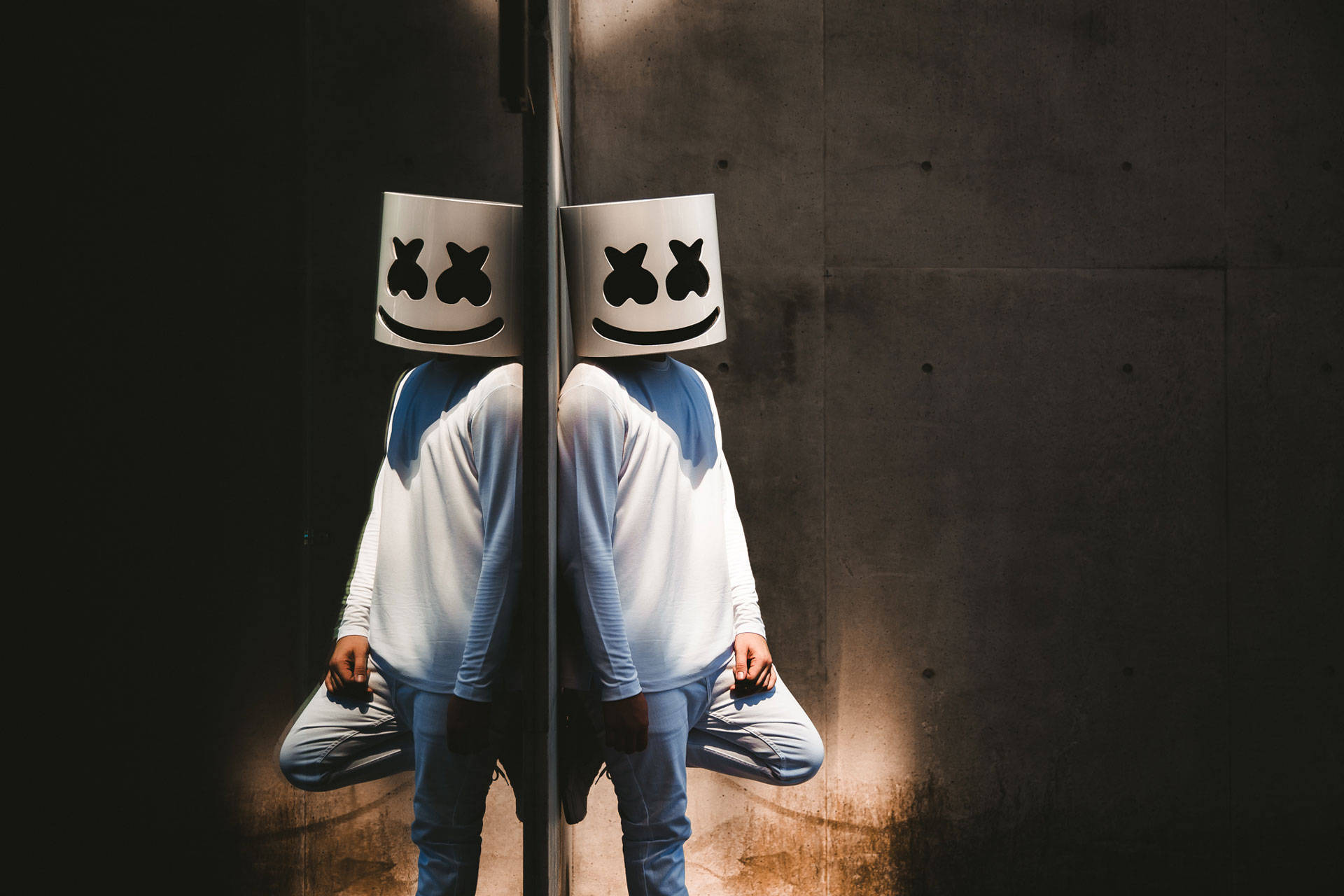 Marshmello 動態圖 桌布 壁紙 — 兩個戴著標誌性白色棉花糖面具的人物背靠背坐在混凝土牆前，牆上沐浴著戲劇性的側光。
