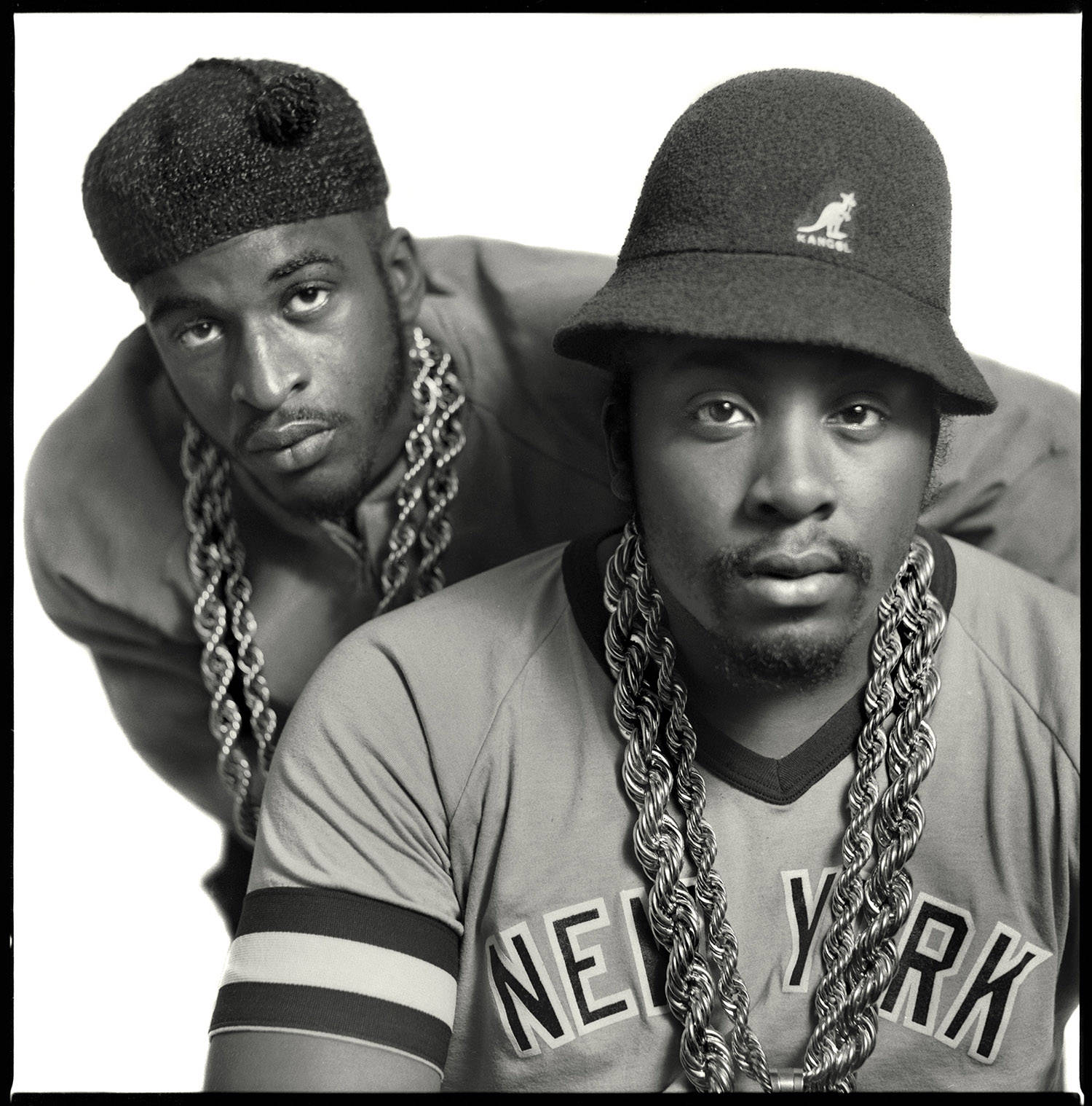 Rappers 桌布 壁紙 — 兩個戴著漁夫帽和粗鏈條的男人在純白背景下直視鏡頭，眼神強烈。