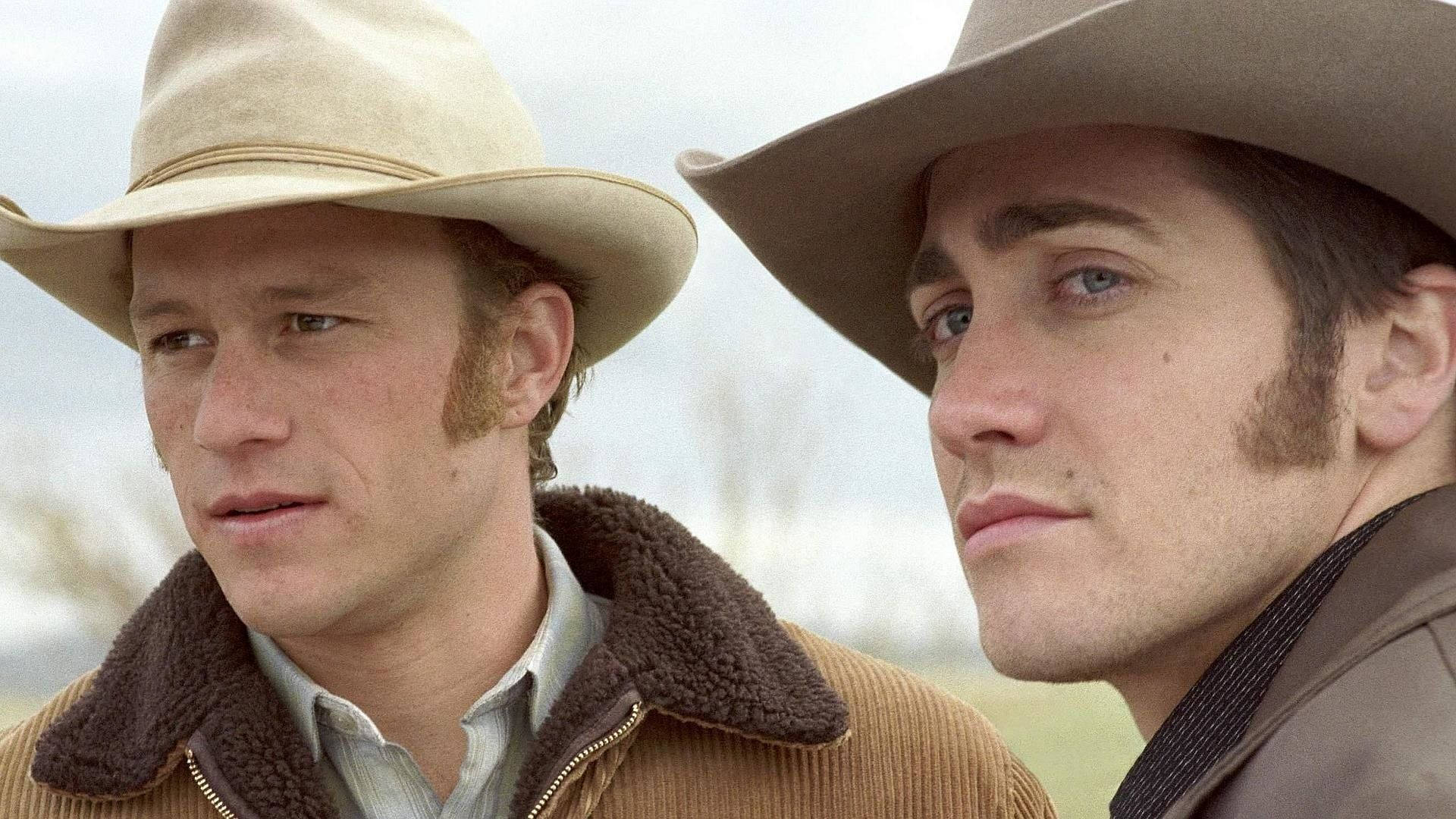 brokeback mountain 桌布 壁紙 — 兩個戴著牛仔帽的男人在模糊的草地背景下，若有所思地望著蒼白的天空。