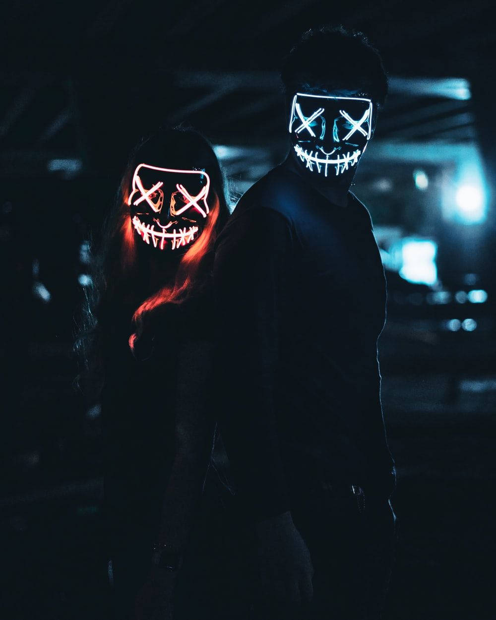 Dark Halloween 桌布 壁紙 — 兩個戴著發光LED面具的人物站在黑暗的城市夜景中，背景有霓虹燈。