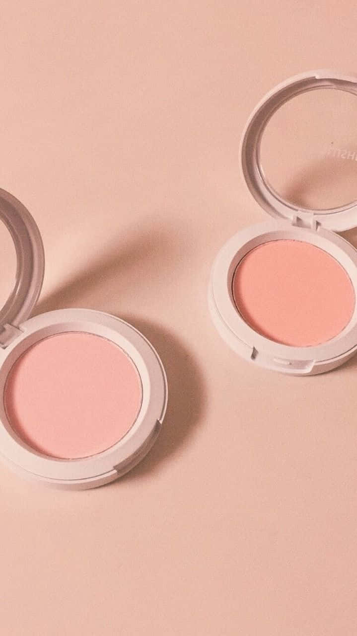 Cosmetic 桌布 壁紙 — 兩個打開的腮紅粉盒，內含柔軟的粉紅色和蜜桃色粉末，放置在相配的淡粉紅色表面上。