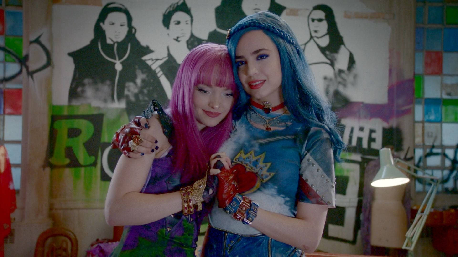 Descendants 桌布 壁紙 — 兩個擁有鮮豔粉紅色和藍色頭髮的女孩在一個佈滿塗鴉的房間裡，在亮著的檯燈旁近距離擺姿勢。