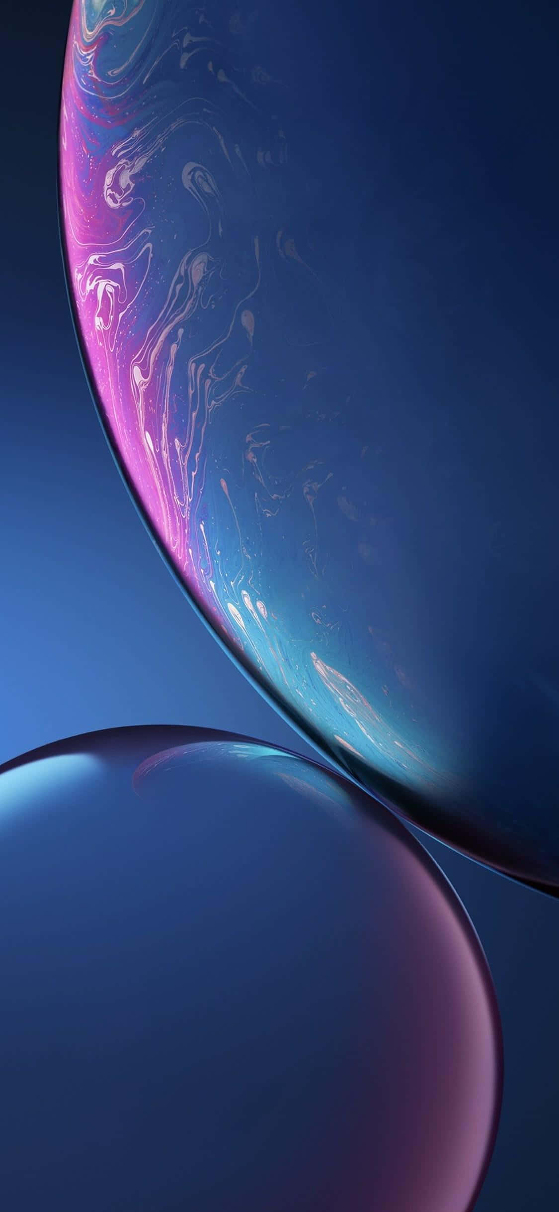 iPhone X 桌布 壁紙 — 兩個有光澤的肥皂泡在深藍色漸變背景上漂浮，帶有旋轉的粉紅色和青色亮點。