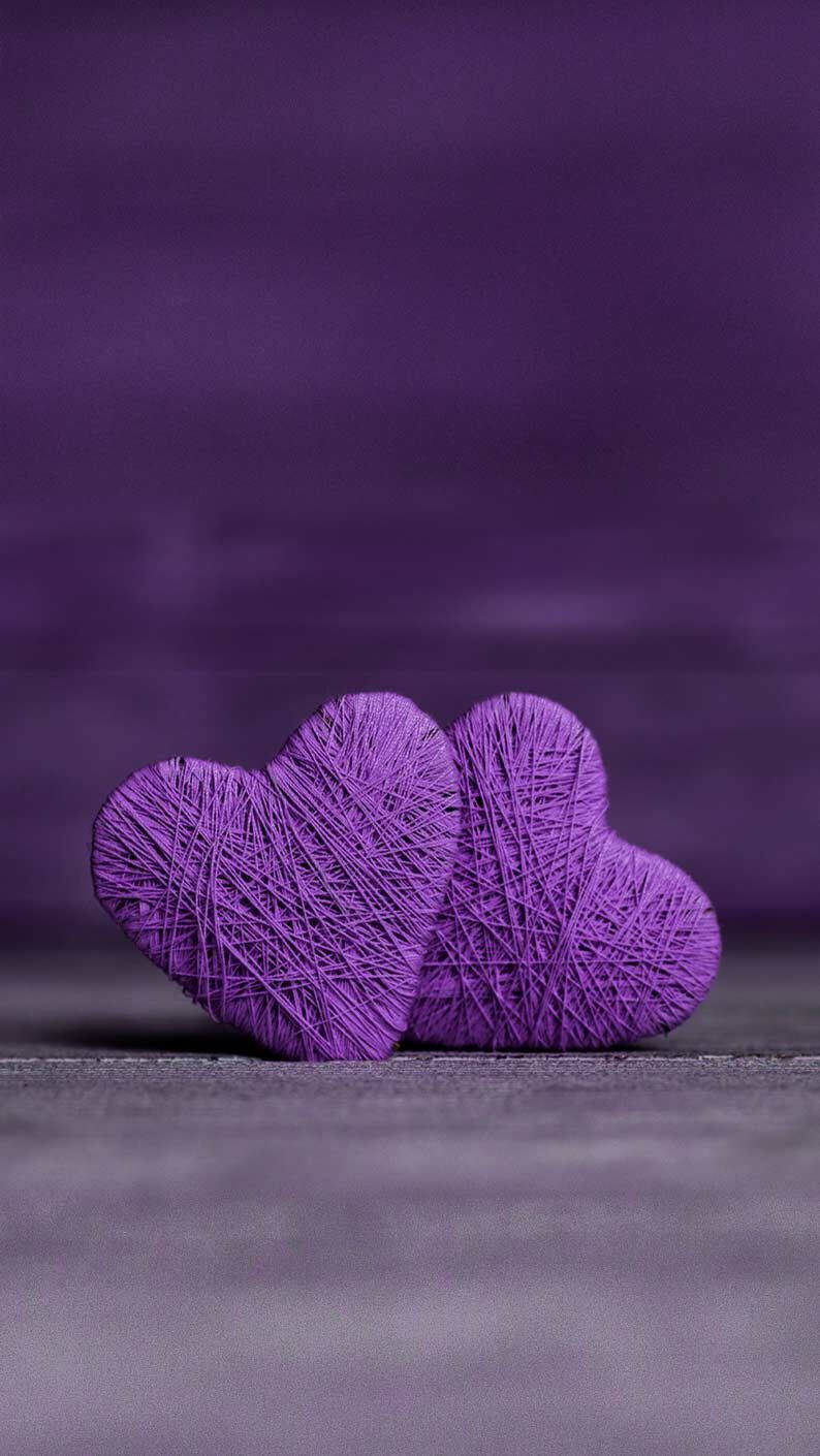 Love Heart 桌布 壁紙 — 兩個有紋理的紫色毛線心形並排放在灰色表面上，背景是模糊的紫色。
