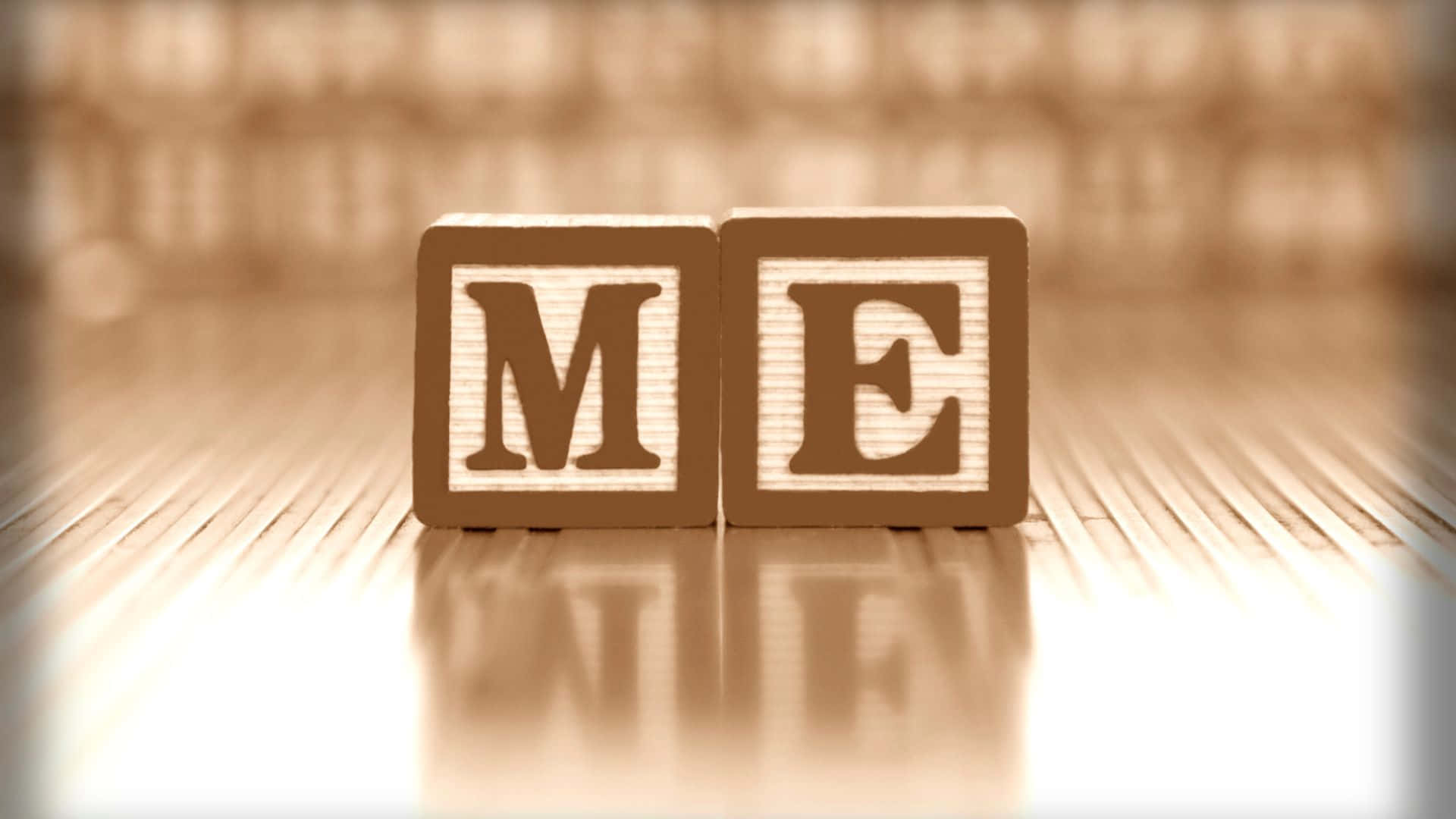 Me 桌布 壁紙 — 兩個木製積木拼出「ME」，放在反光的木質表面上，背景是模糊的書架。