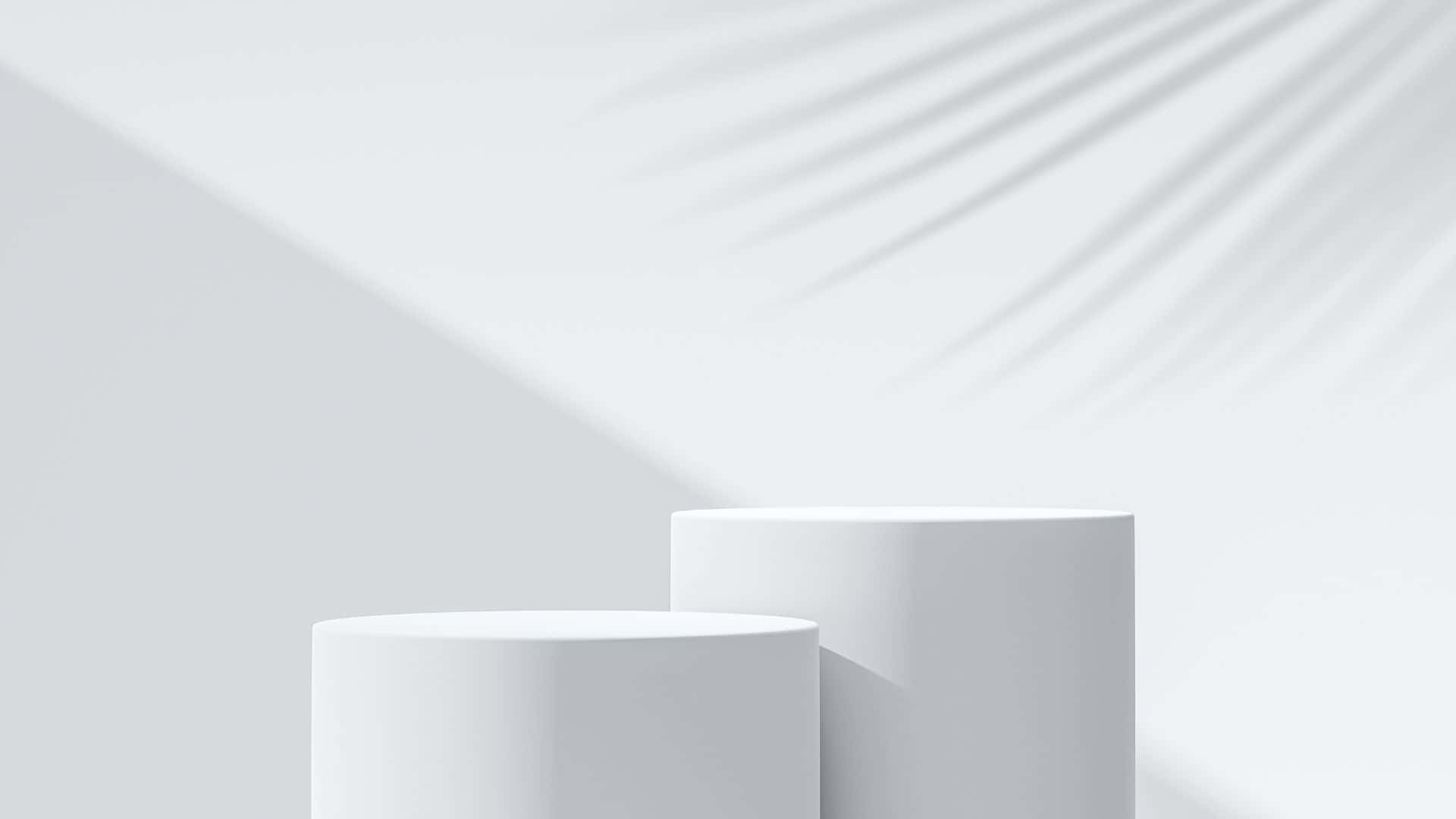 Products 桌布 壁紙 — 兩個極簡白色圓柱形底座在明亮的牆壁上投射出柔和陰影，牆上有棕櫚葉剪影。